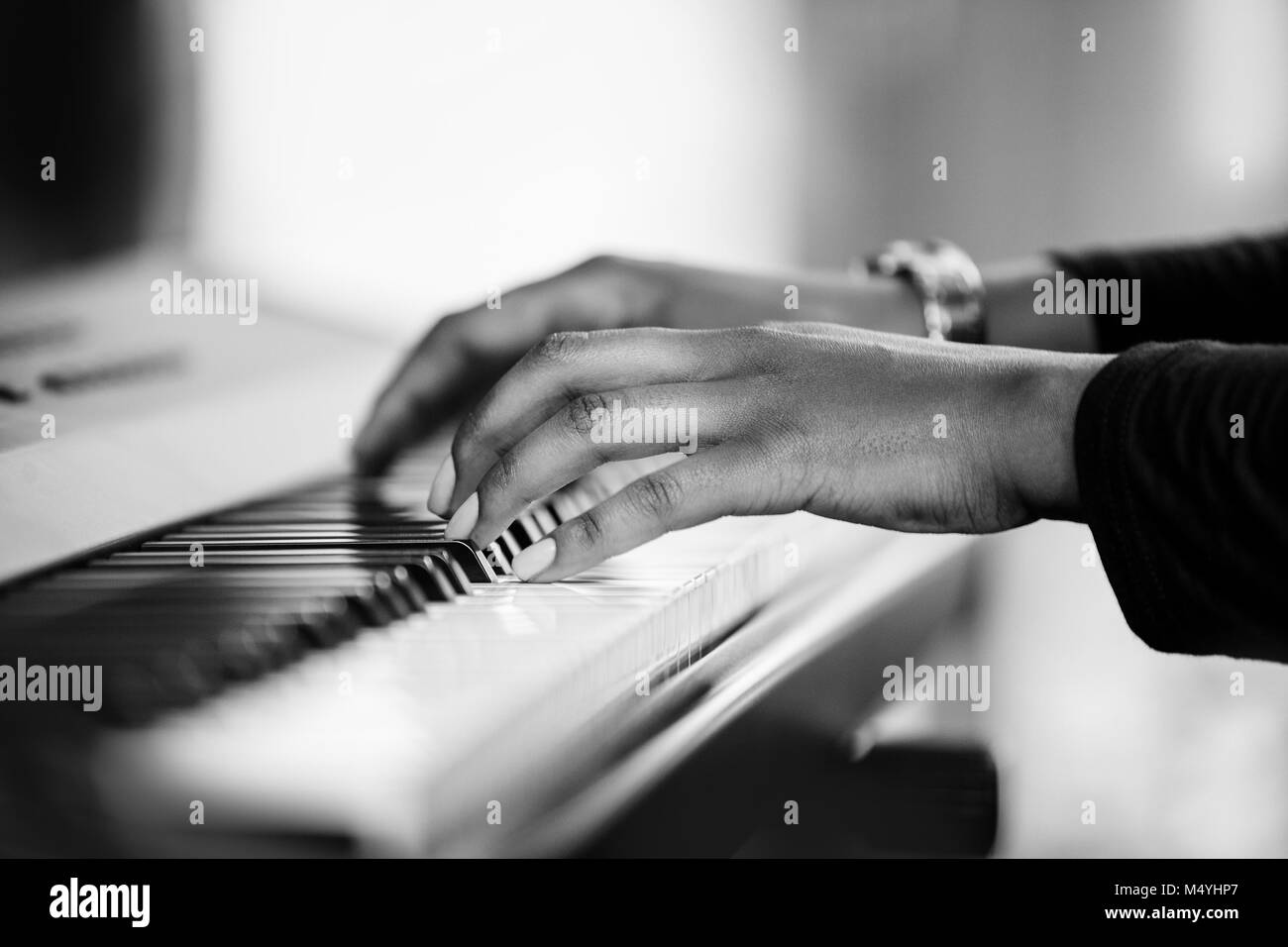 Female African hands playing a piano. Black and white image of pianists hands. Stock Photo