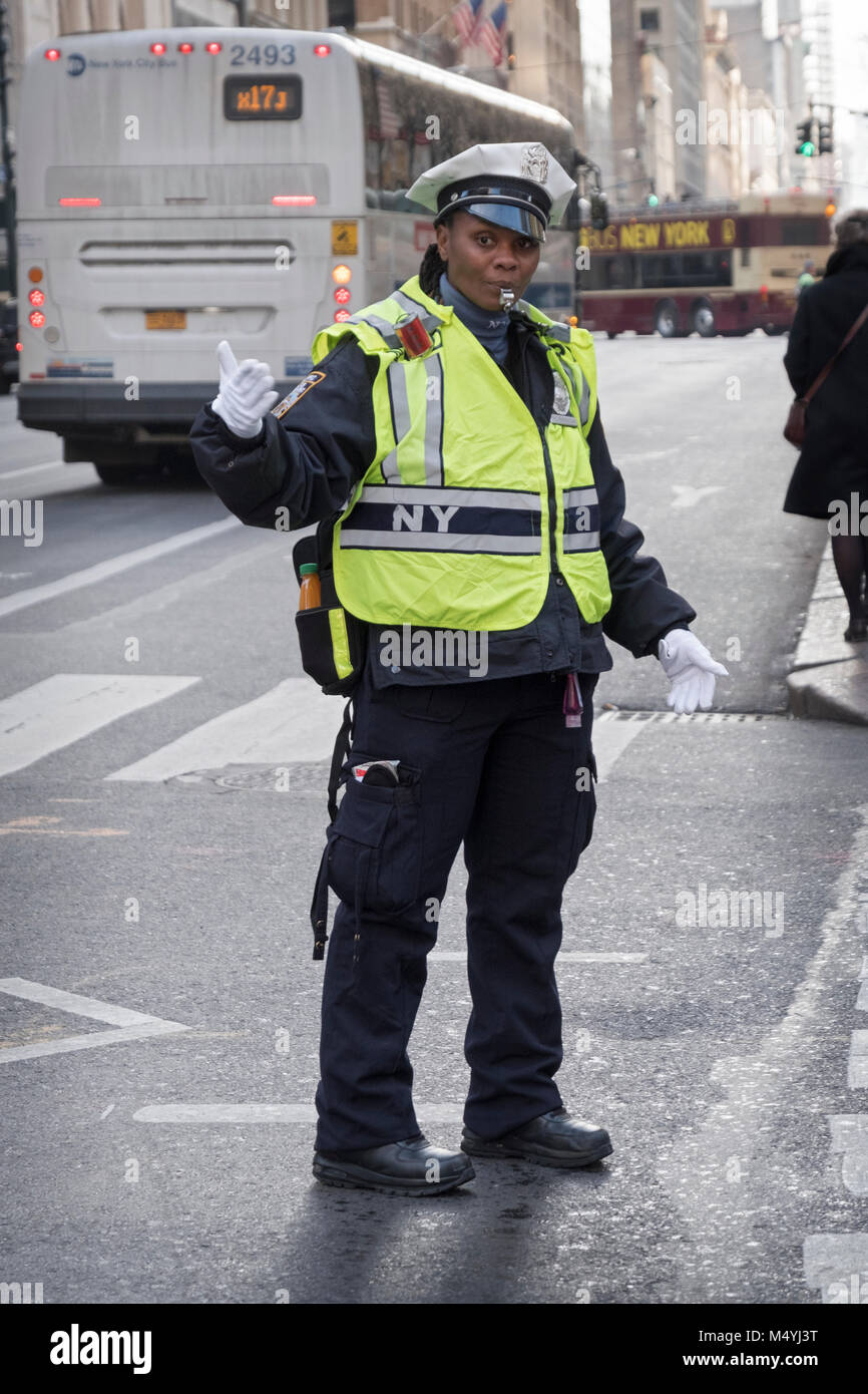 A female traffic cop directing traffic on Fifth Avenue in Midtown Manhattan, New York Citysafety vest, whistle, blows, blowing, outside, outdoors, out Stock Photo