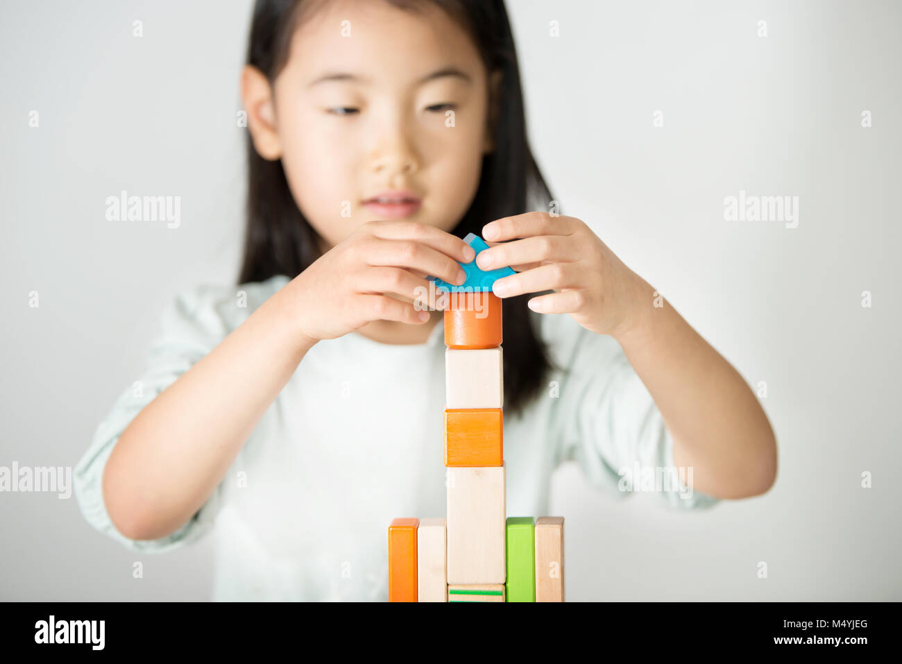 little Asian girl playing colorful wood blocks Stock Photo