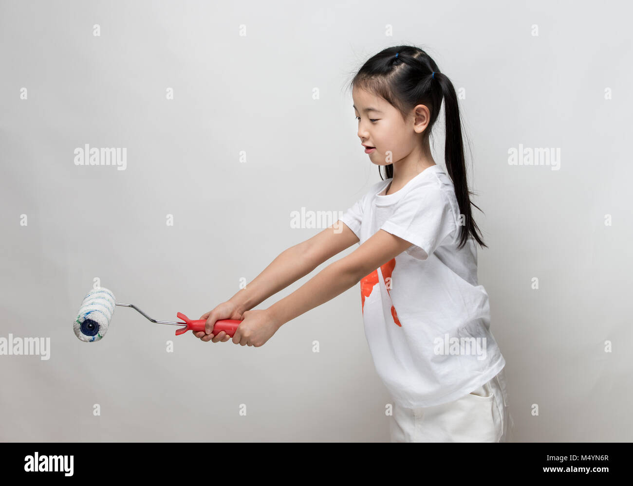 Cute asian girl holding paint roller Stock Photo