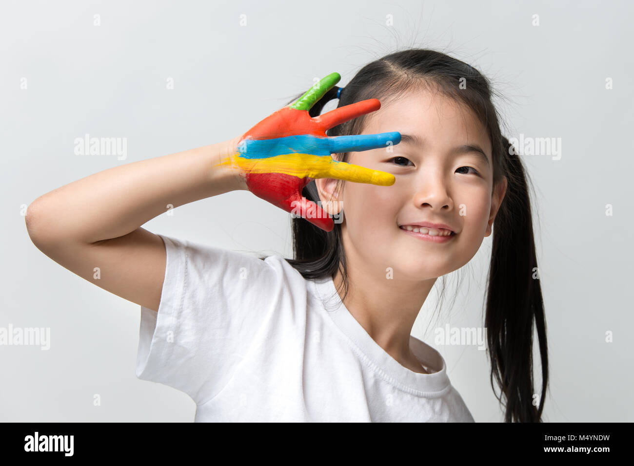 Little Asian girl with hands painted in colorful paints Stock Photo