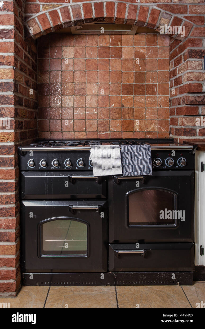 Range cooker in a red brick kitchen. Stove and cooker. Stock Photo