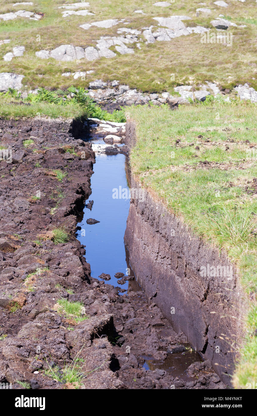 A peat trench cut into the moorland on the Isle of South Uist, Outer Hebrides, Scotland, UK Stock Photo