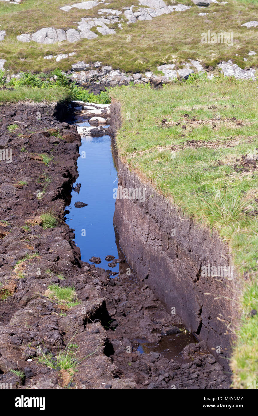 A peat trench cut into the moorland on the Isle of South Uist, Outer Hebrides, Scotland, UK Stock Photo