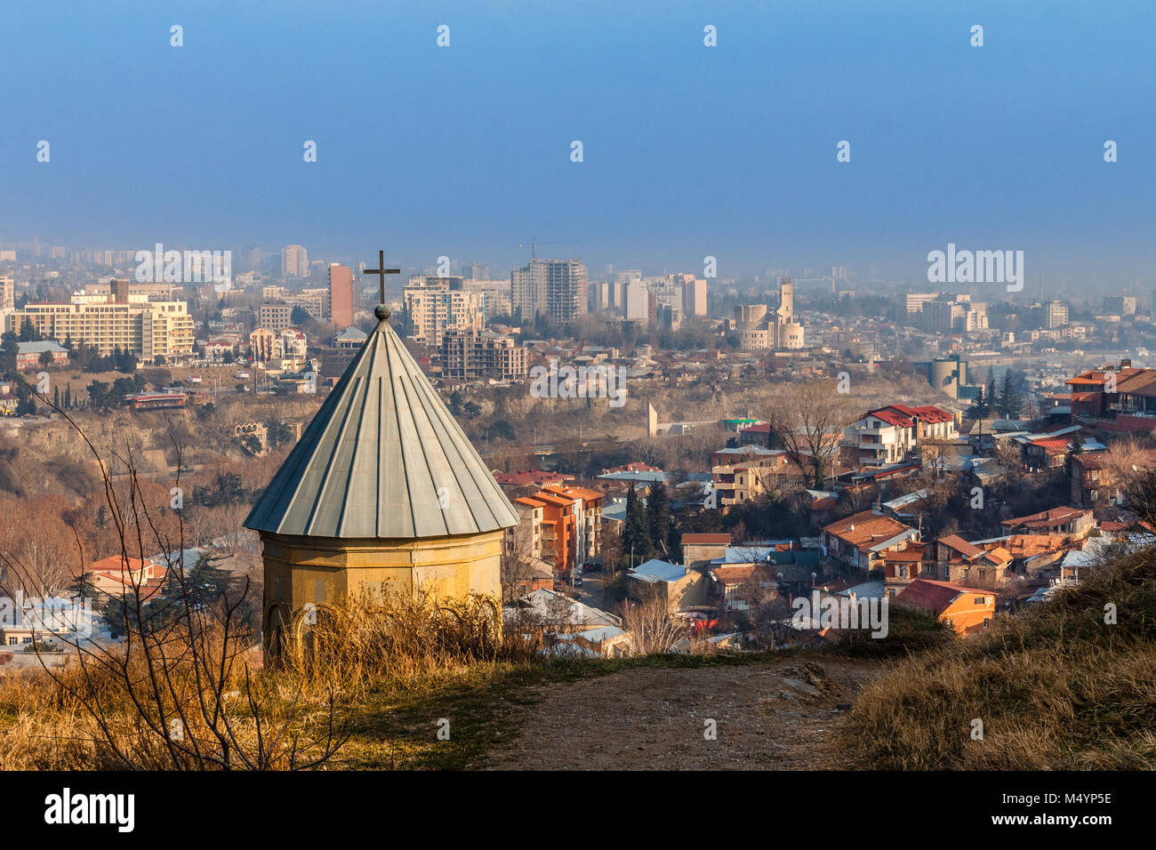 Old church dome with the cross and growing residential area with modern buildings, Tbilisi, Georgia Stock Photo