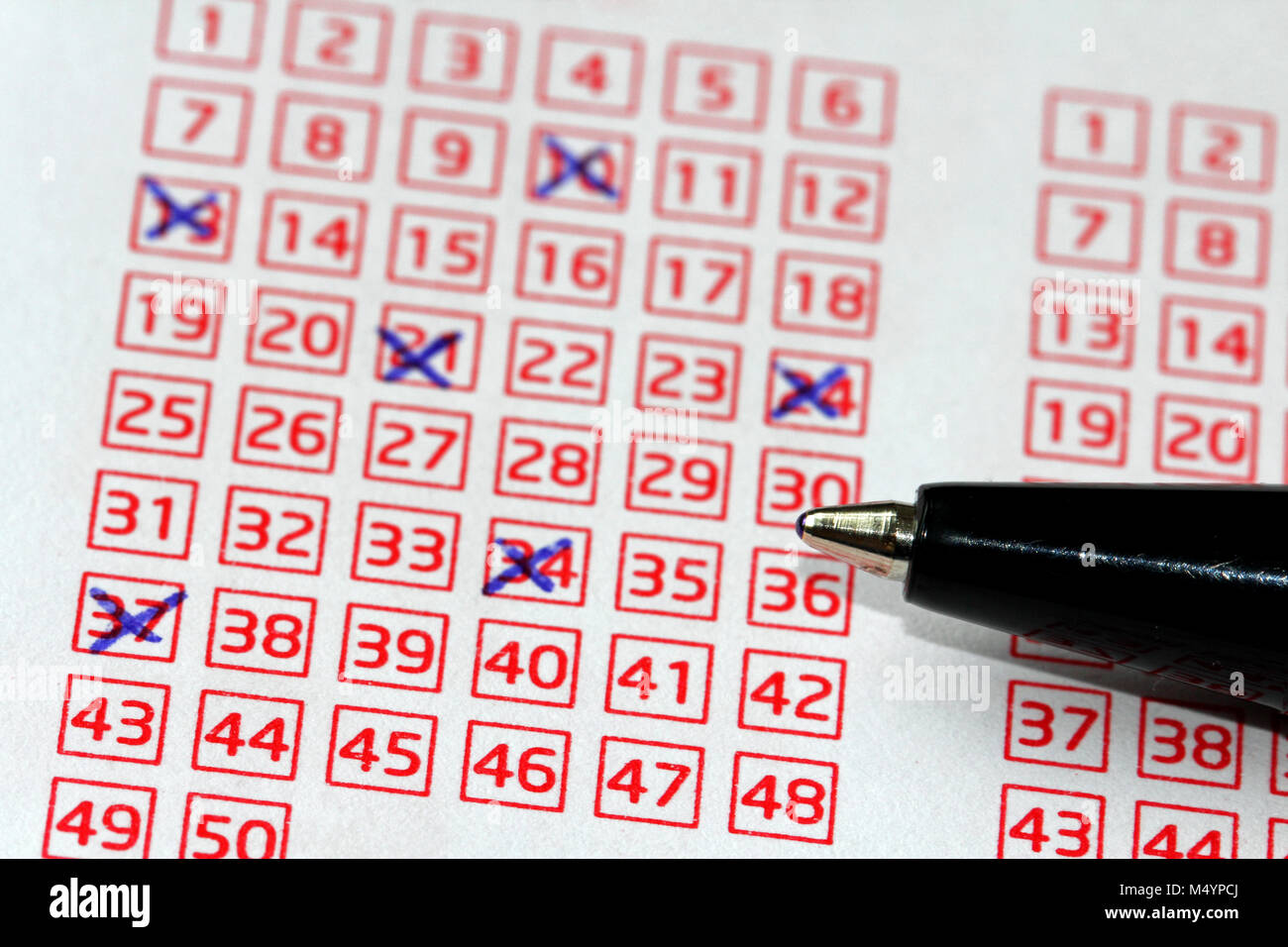 Pen and lucky numbers marked on a lottery coupon, shallow depth of field. Stock Photo