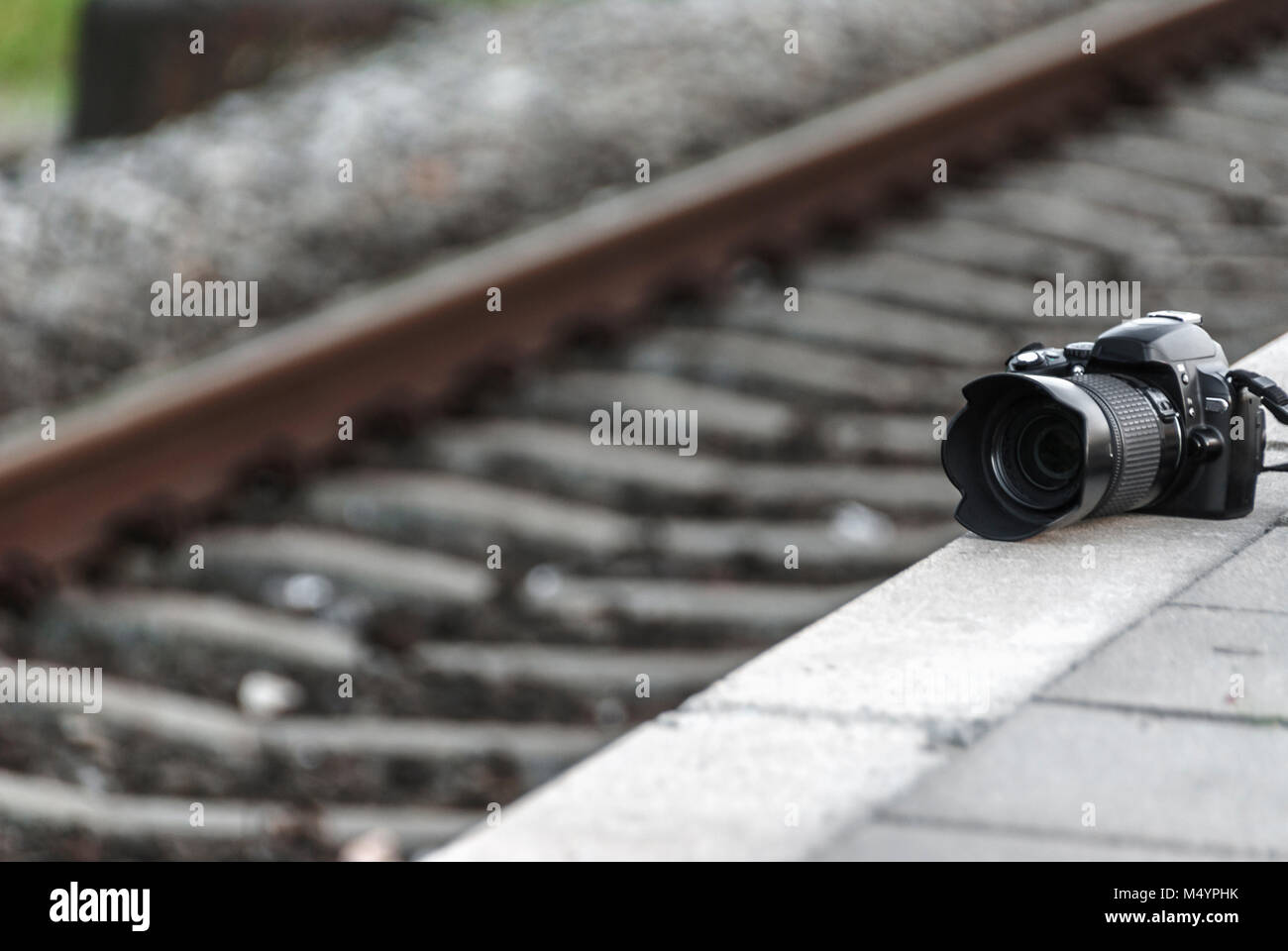 camera placed on a side walk next to a railroad track Stock Photo