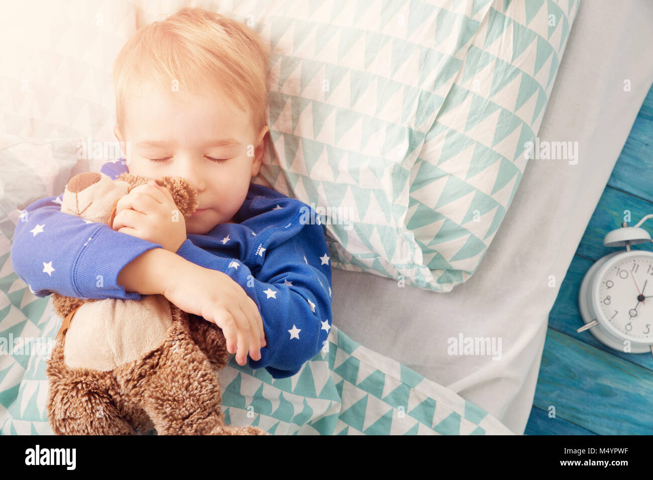 three years old child sleeping in bed with alarm clock Stock Photo Alamy