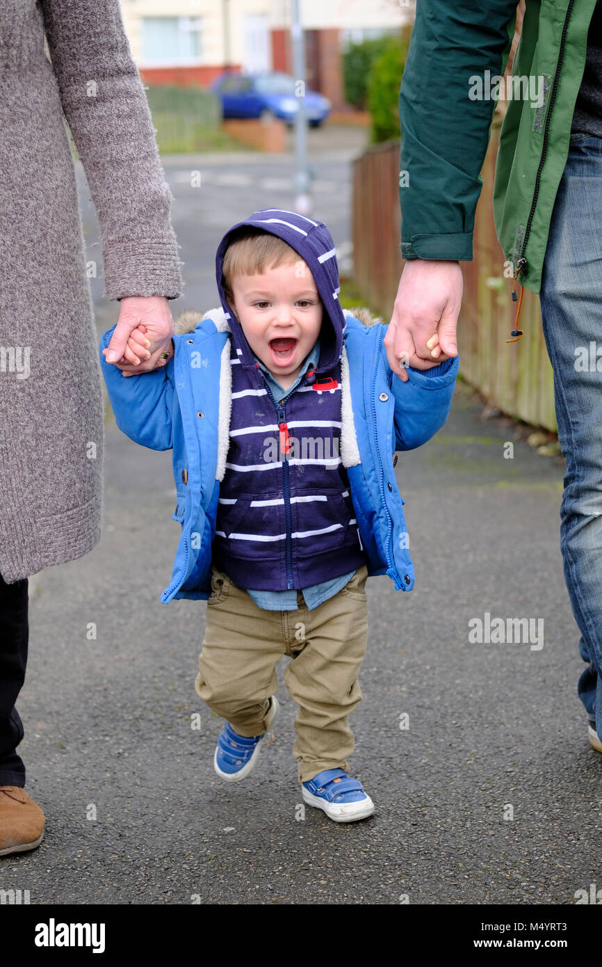 Toddler holding hands and walking outside Stock Photo