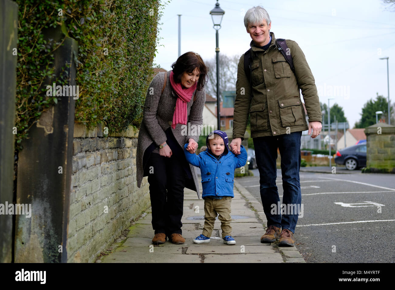 toddler walking along street with grandparents Stock Photo