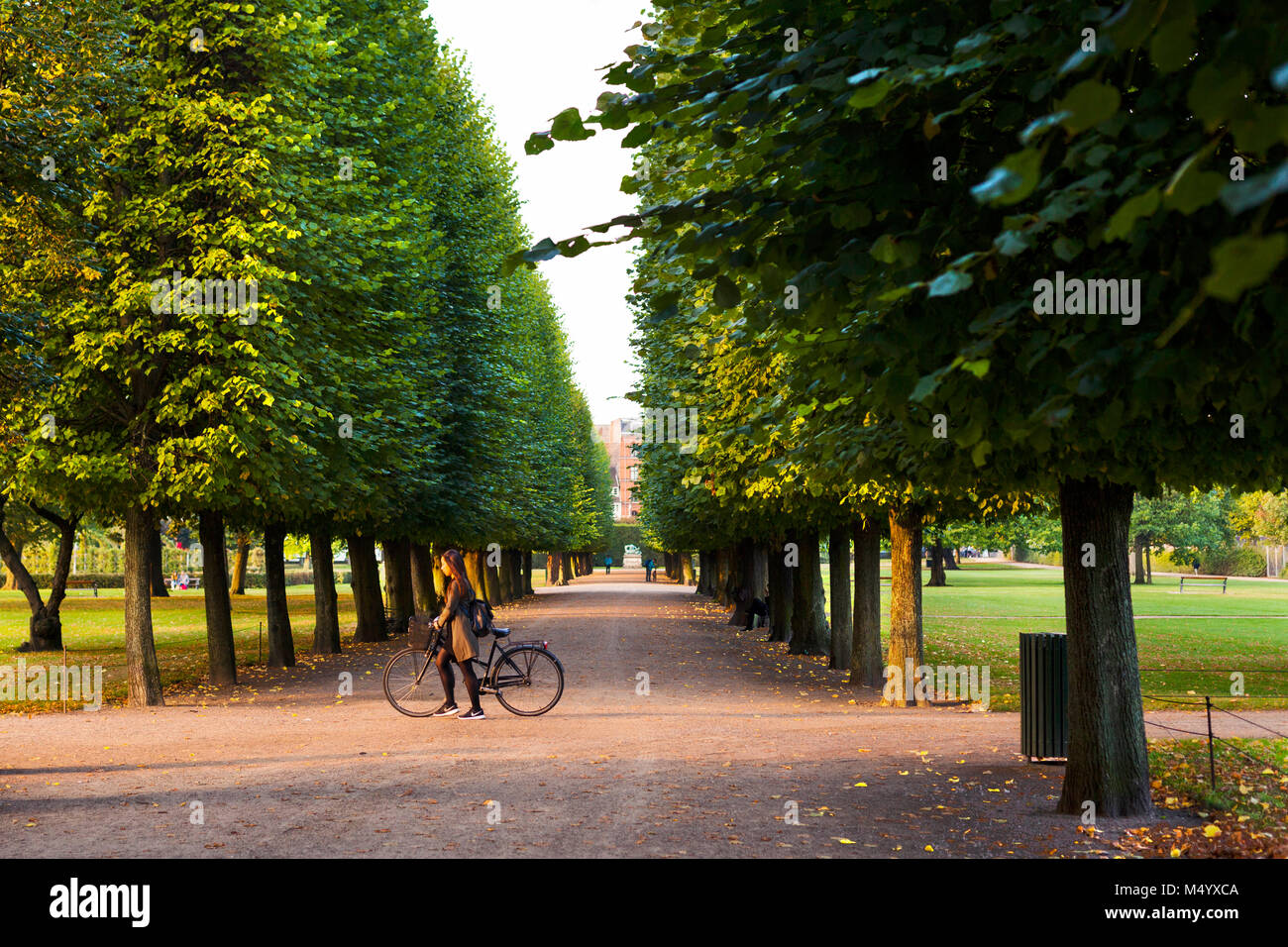 Woman walking with her bicycle through Kongens Have, (Kings Garden) in Copenhagen, Denmark Stock Photo