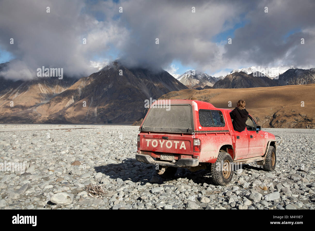 SUV driving on rocks with mountains in background, New Zealand Stock Photo