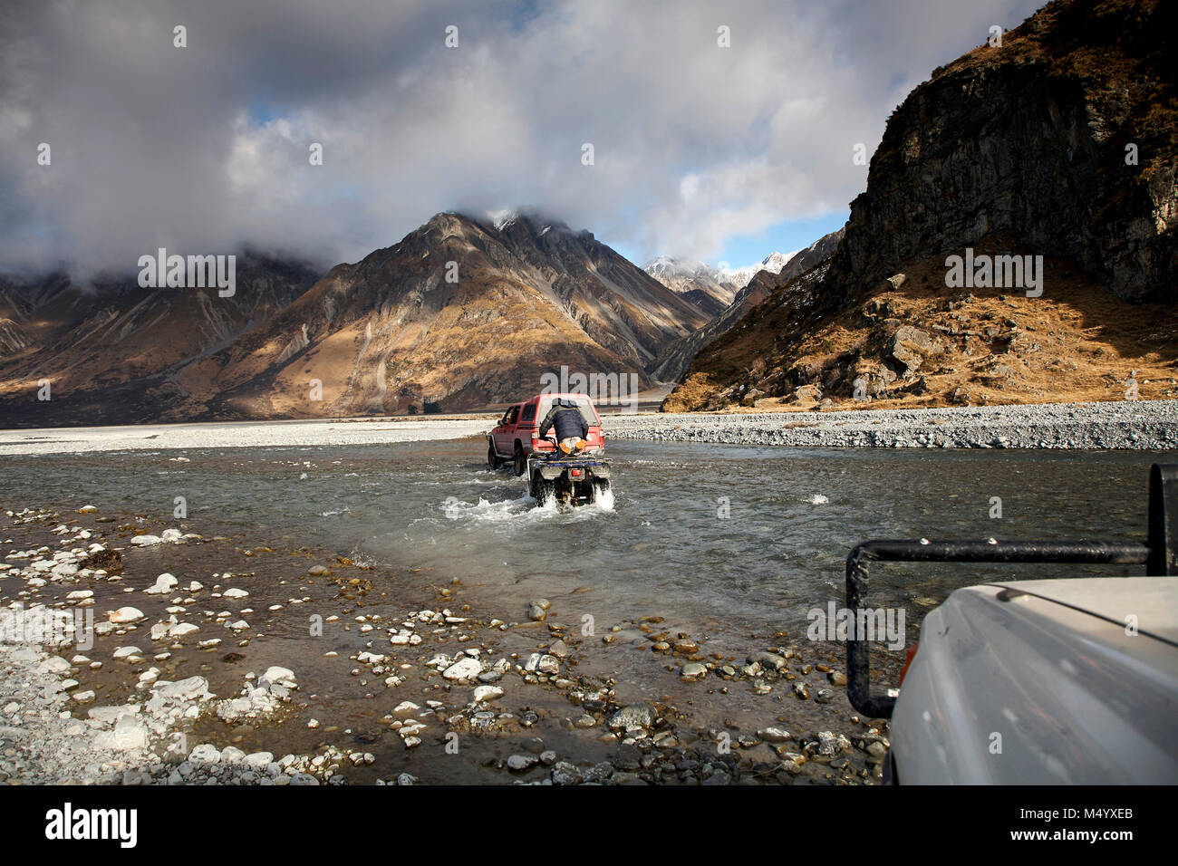 4x4 car and quadbike crossing river during hunting trip, New Zealand Stock Photo