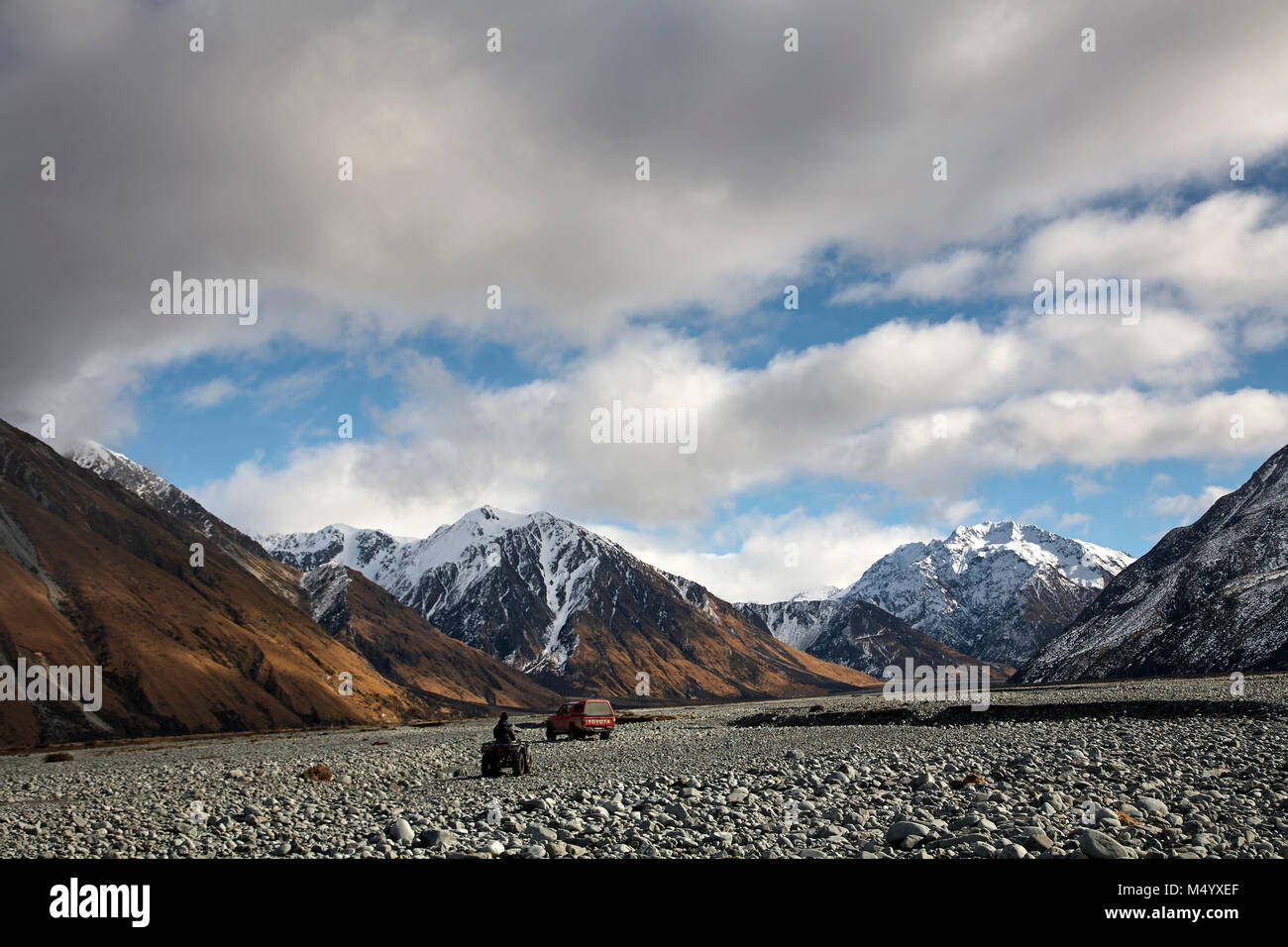 4x4 car and quadbike driving in rocky scenery with mountains during hunting trip, New Zealand Stock Photo