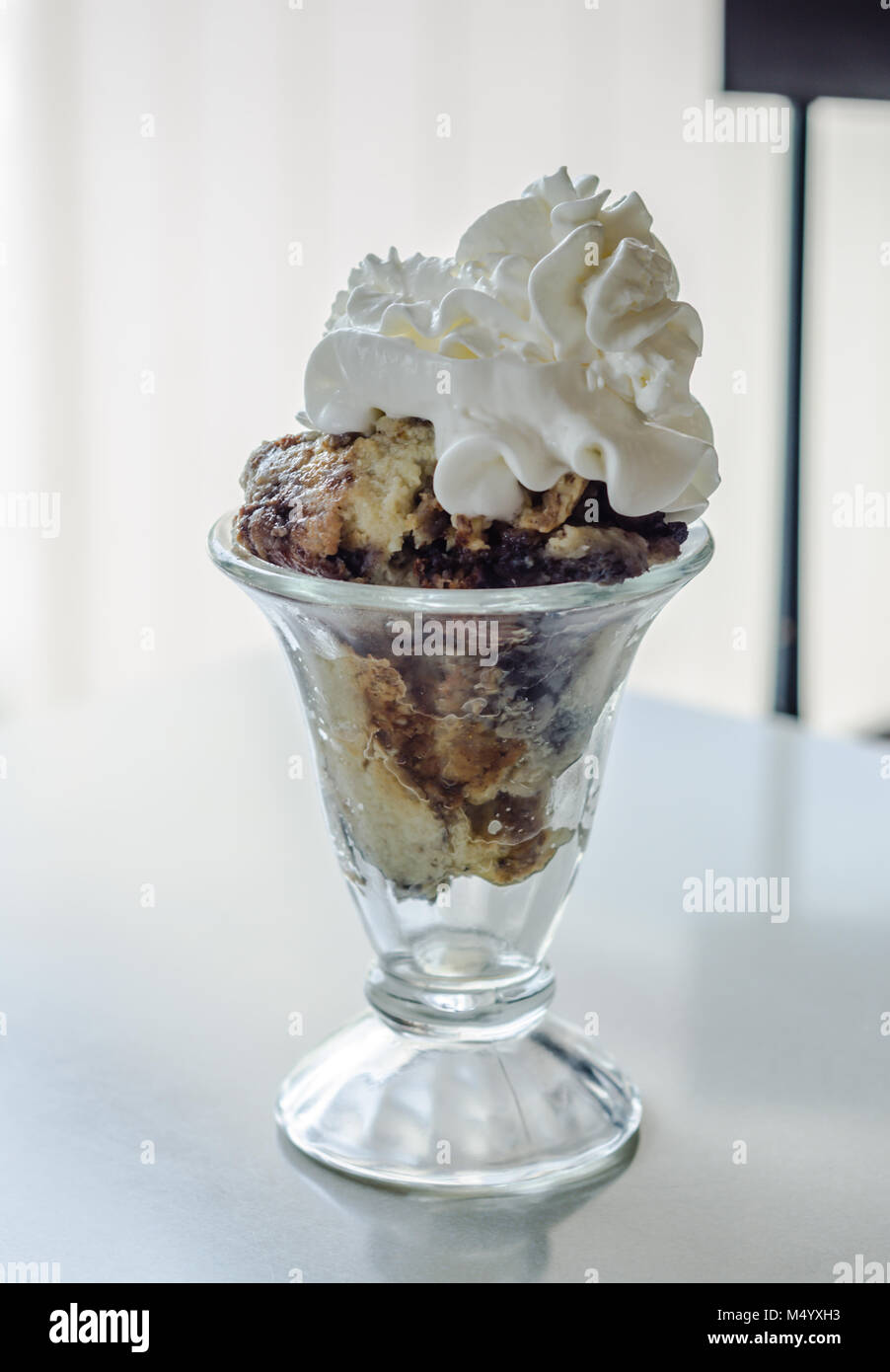 Layers of blueberry cobbler topped with fresh whipped cream in a parlor ice cream glass. Stock Photo