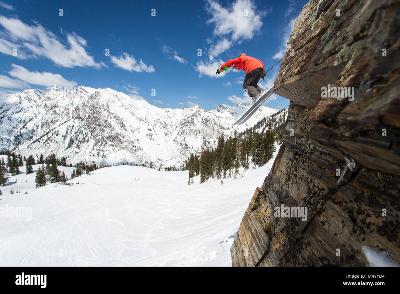 Skier jumping off cliff against snowcapped mountain range, Utah, USA Stock Photo