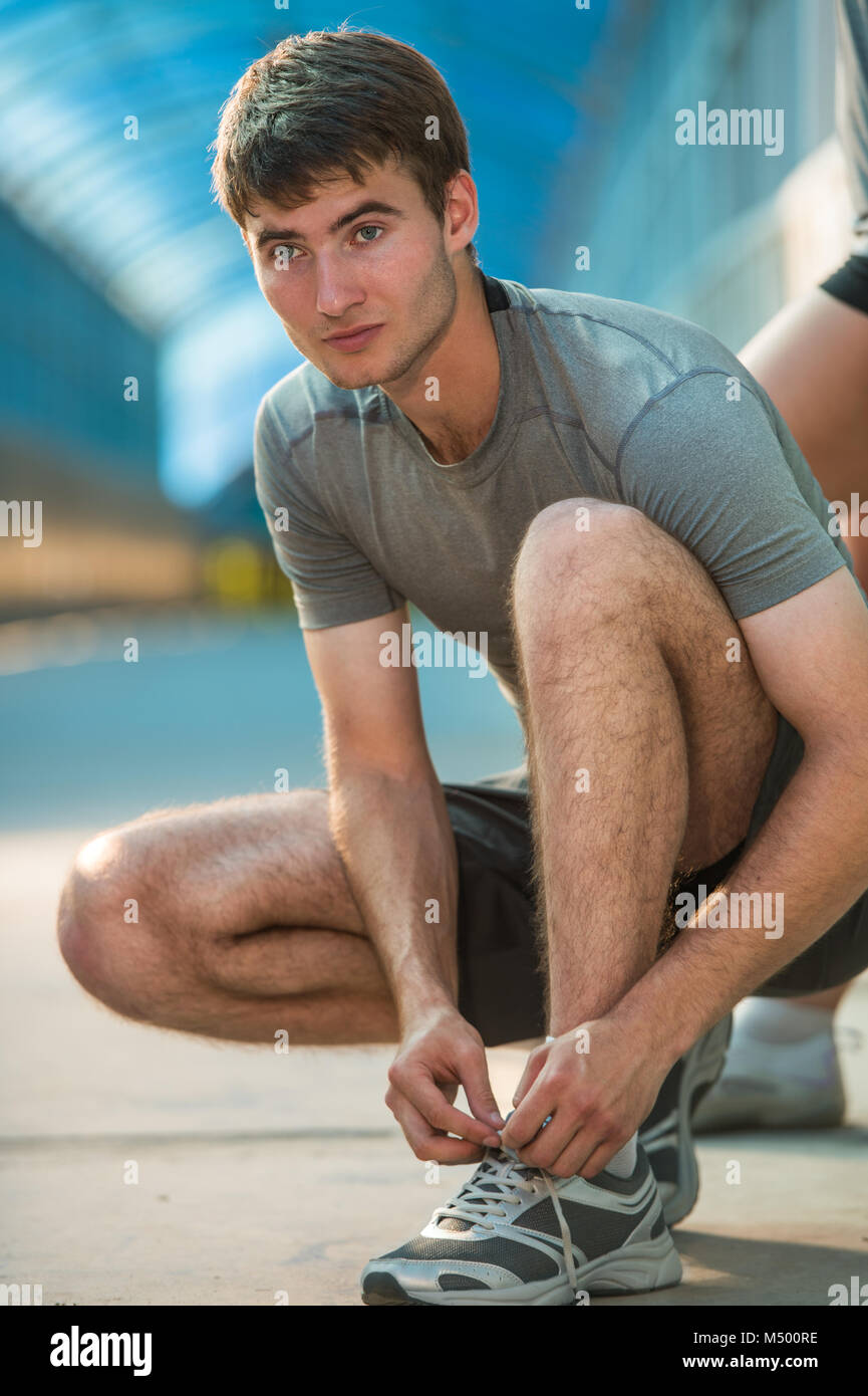 Handsome man lacing his shoes before running outdoors Stock Photo - Alamy