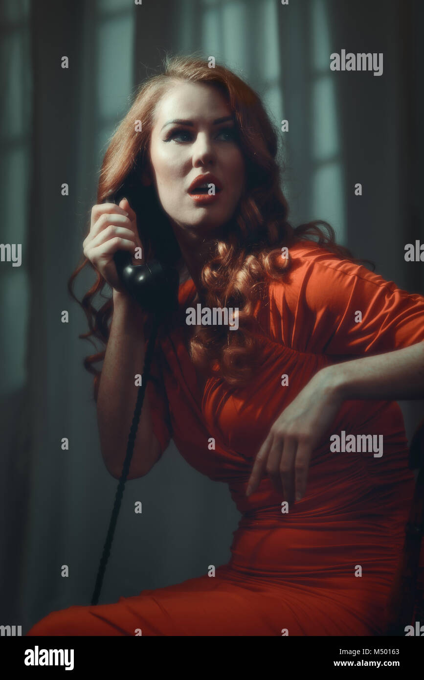 Film Noir cinematic look of woman with long red hair on telephone Stock Photo