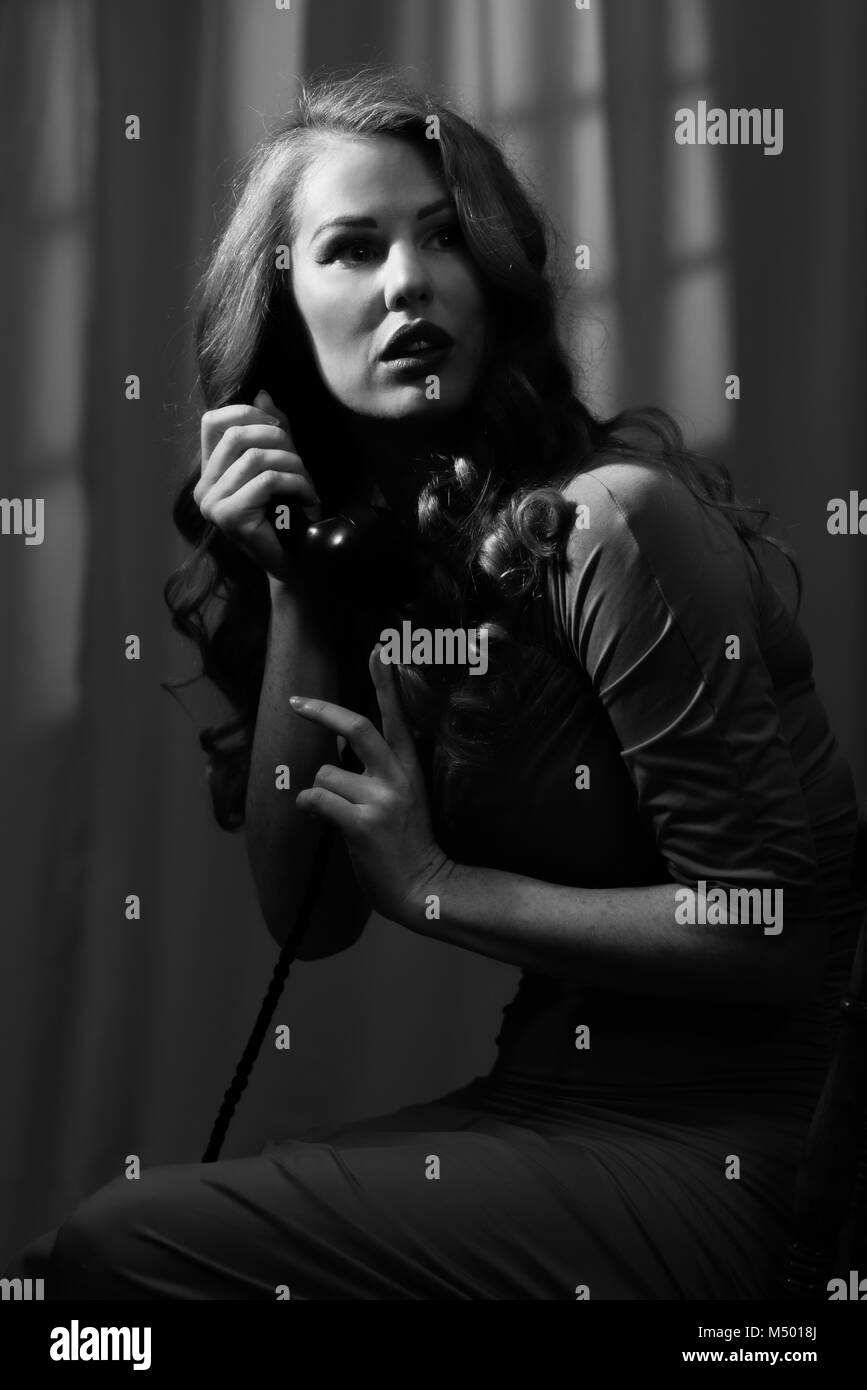 Film Noir style image of woman with long hair on telephone Stock Photo