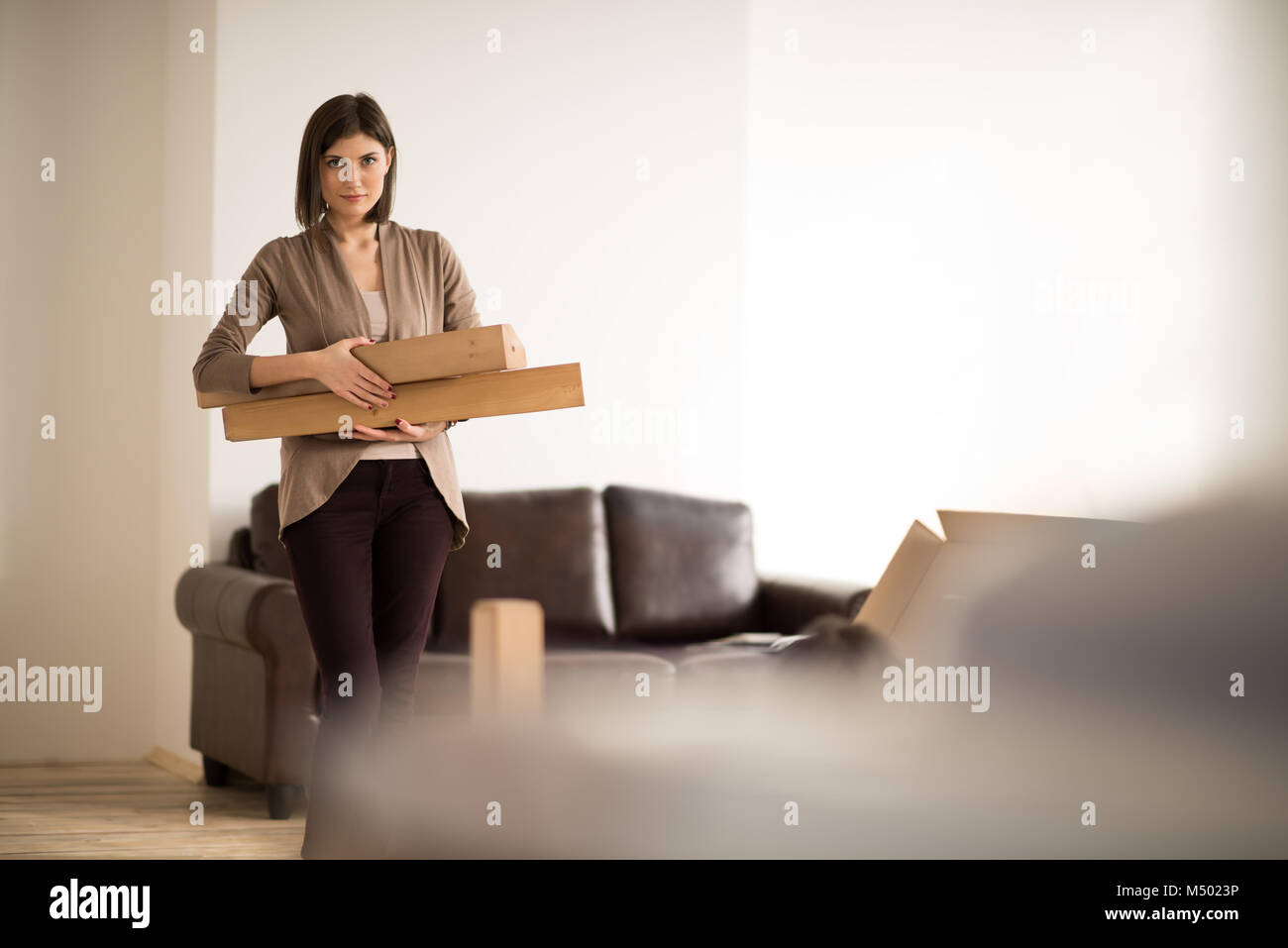 Cheerful woman holding a cardboard box while moving in new home Stock ...