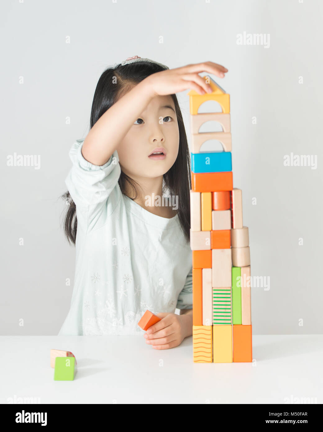 little Asian girl playing colorful wood blocks Stock Photo