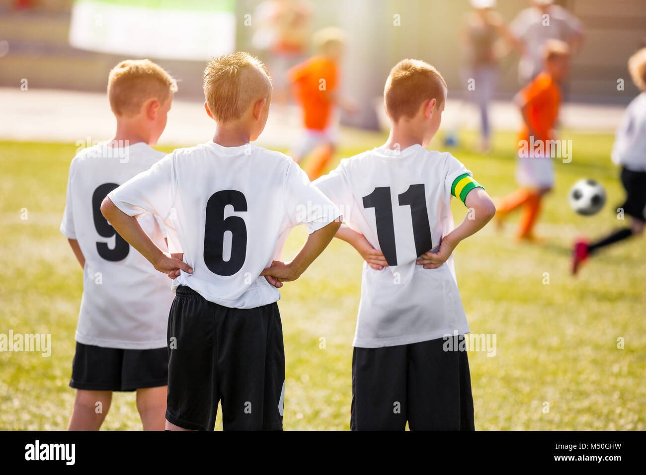Kids Soccer Team Players Standing on Grass Pitch on a Sunny Day. Young Boys Watching Soccer Match. Youth Footballers of Soccer Academy. Football Tourn Stock Photo