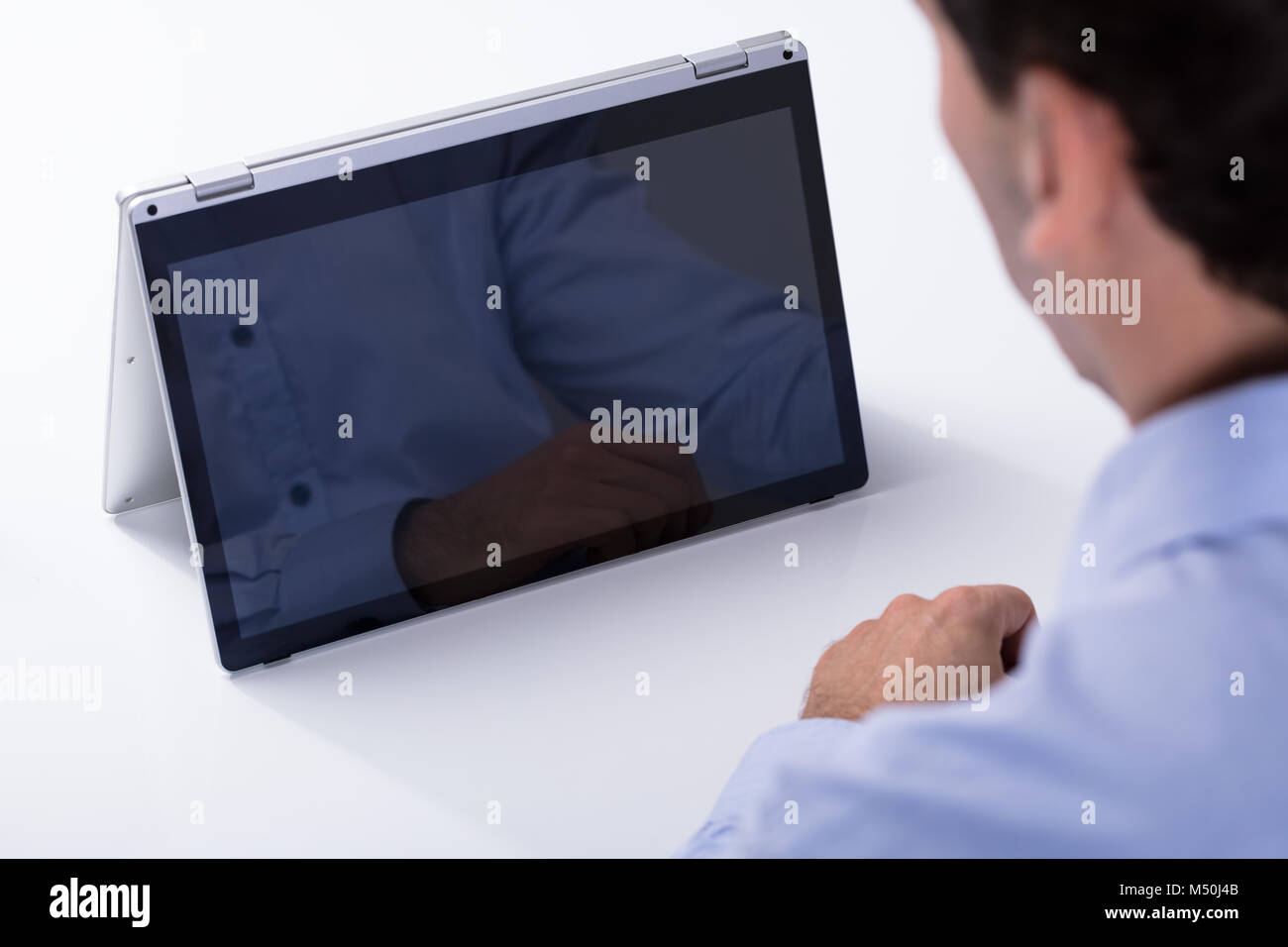 Rear View Of A Man Looking At Blank Hybrid Laptop Over The White Desk ...