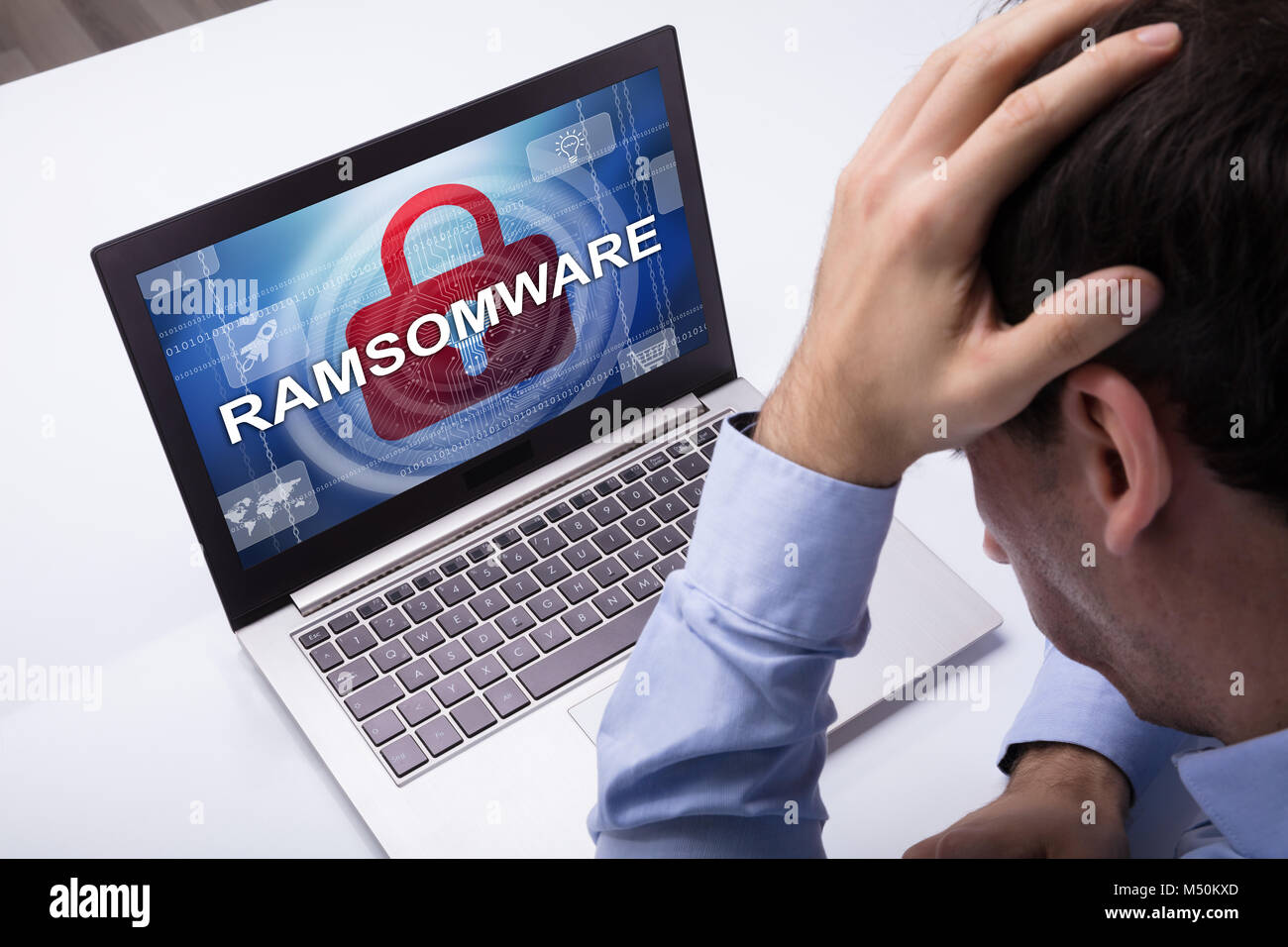 Worried Businessman Looking At Laptop With Ramsomware Word On The Screen At The Workplace Stock Photo