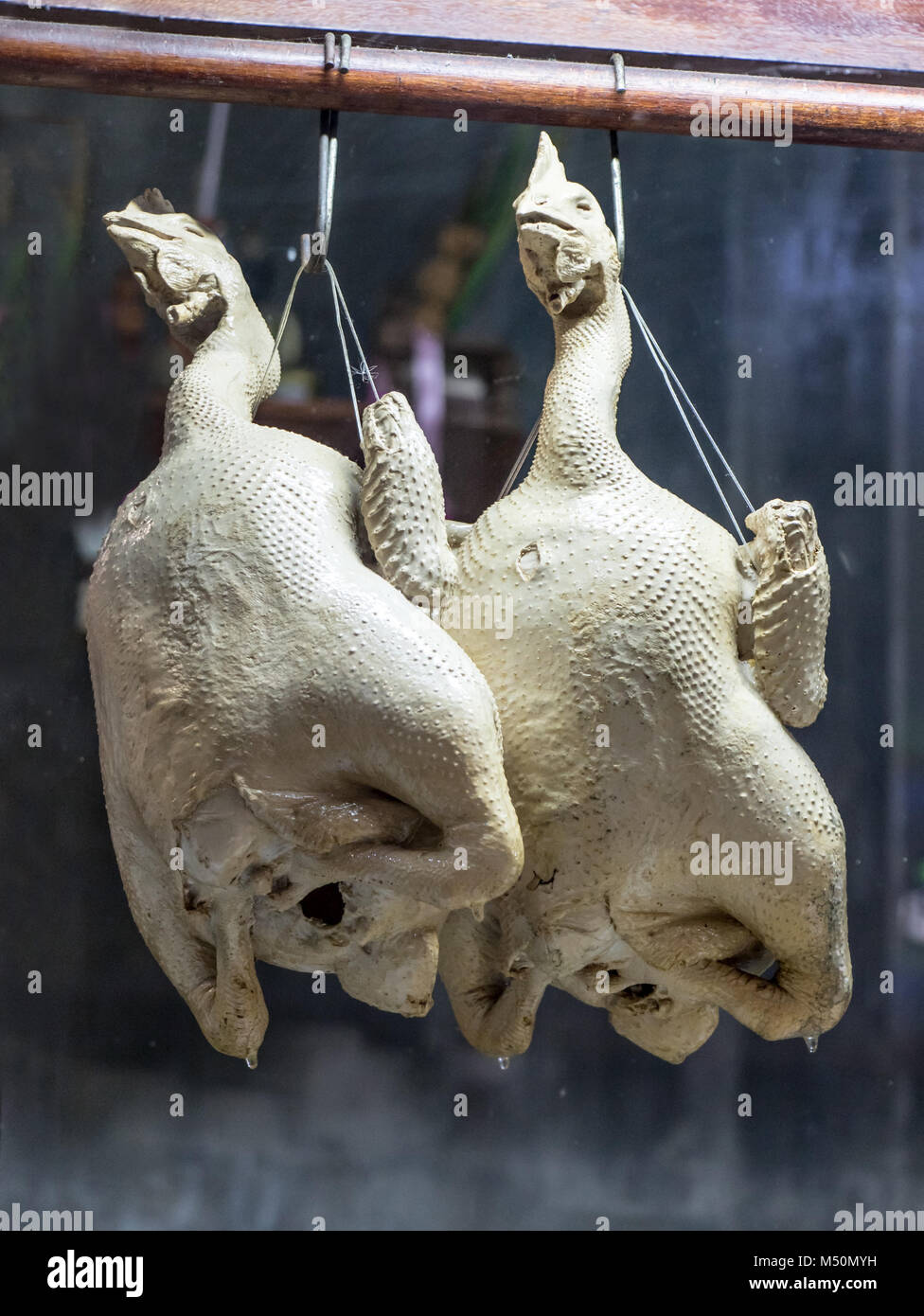 Offer of poultry in an Asian restaurant. The whole chick hangs in the showcase. Stock Photo