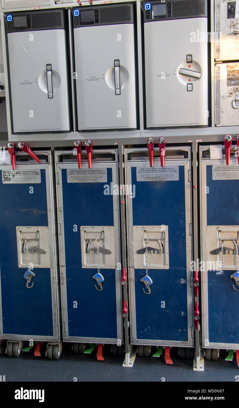 Provision cabinetss on the airplane. Food in box for passengers on the plane. Storage space on the aircraft with trolleys with lunch. Stock Photo