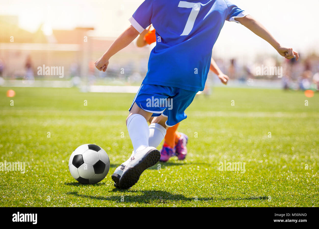 Football player running the ball and kicking towards opponents goal