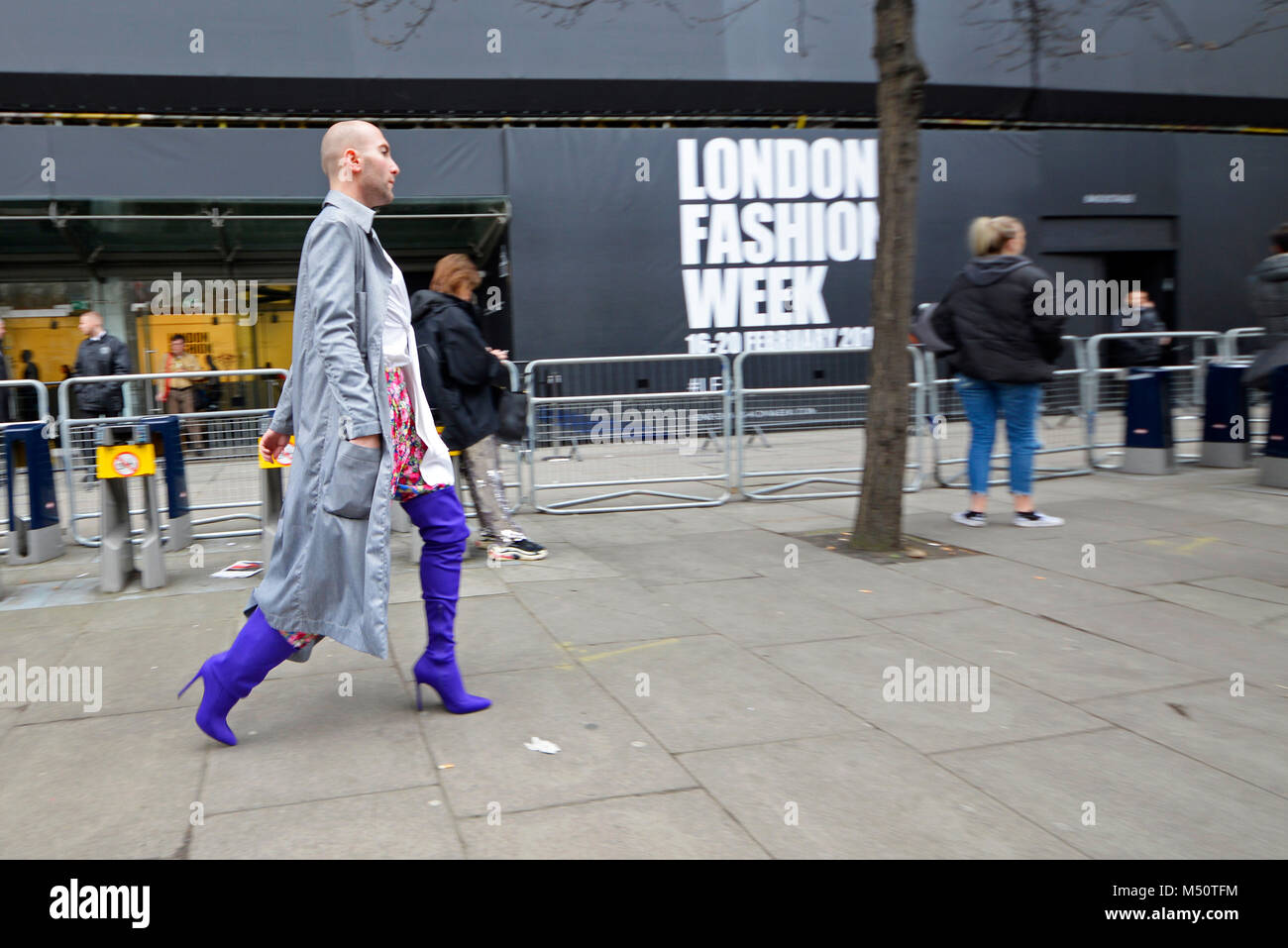 Man in high heeled thigh high feminine boots passing the London Fashion Week venue The Store. Male walking past in ladies boots. Cross dresser Stock Photo