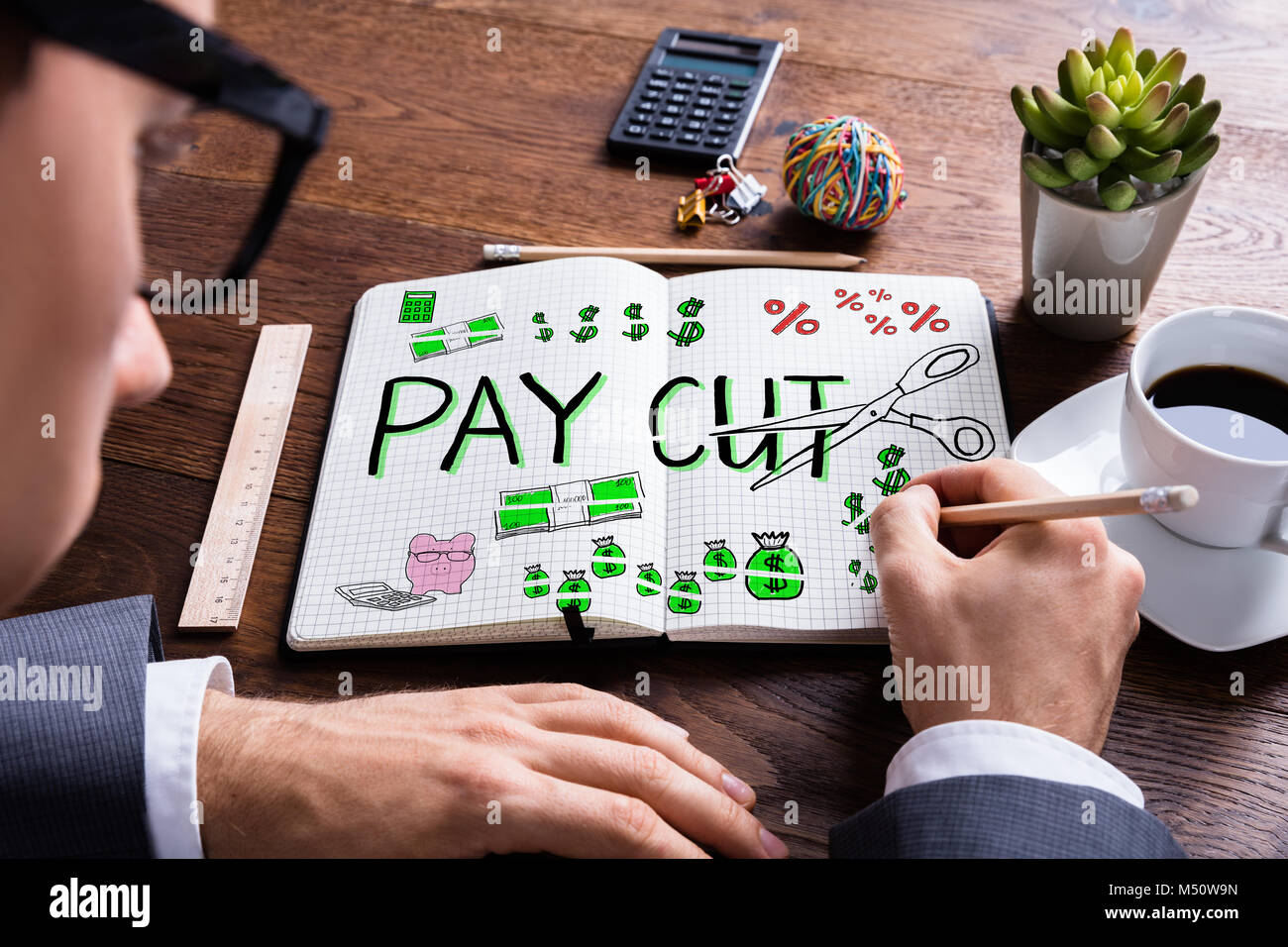 Man Drawing Salary Paycut In Diary At Desk Stock Photo