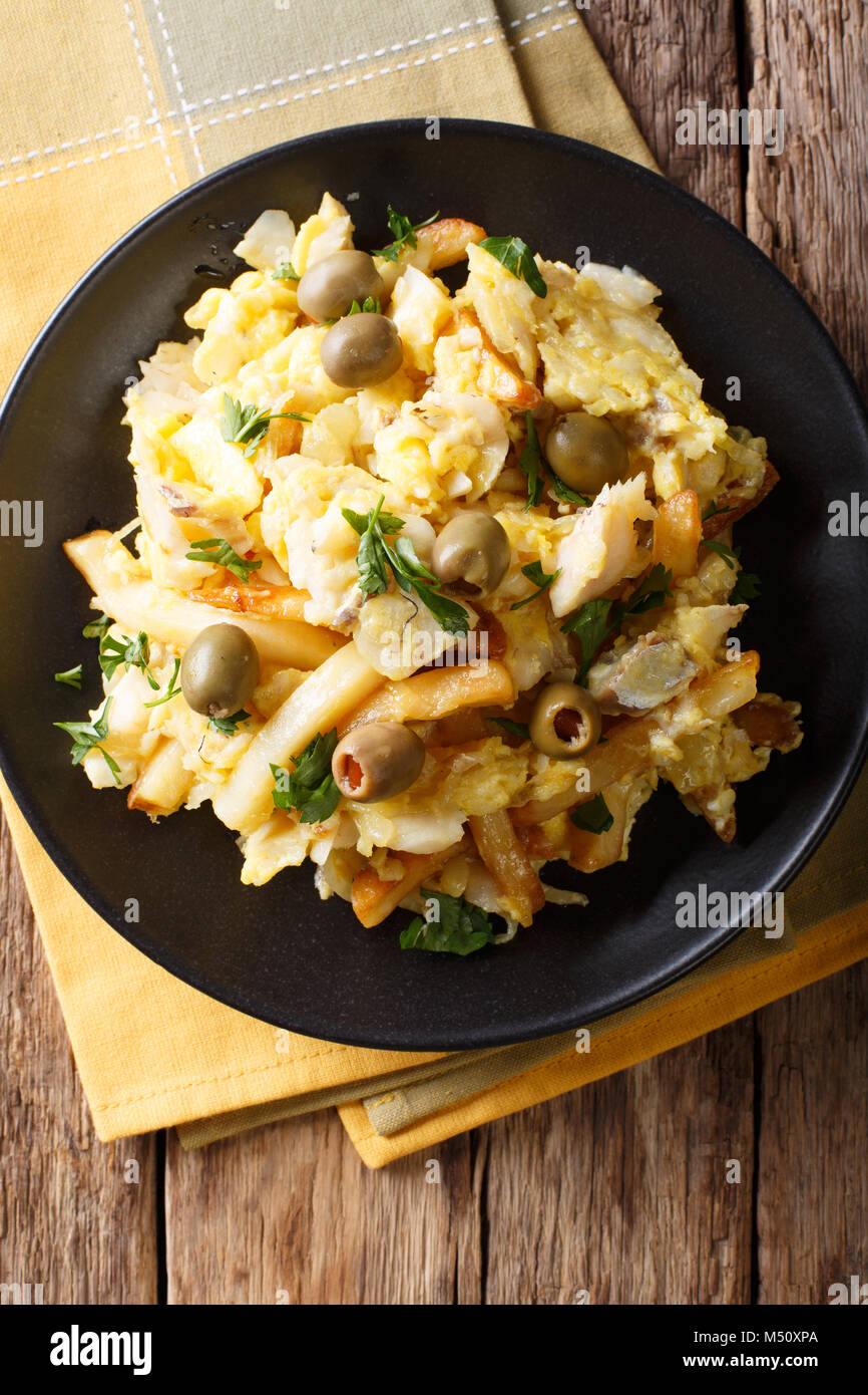Portuguese food fried shredded cod with french fries, onions and eggs on a plate closeup