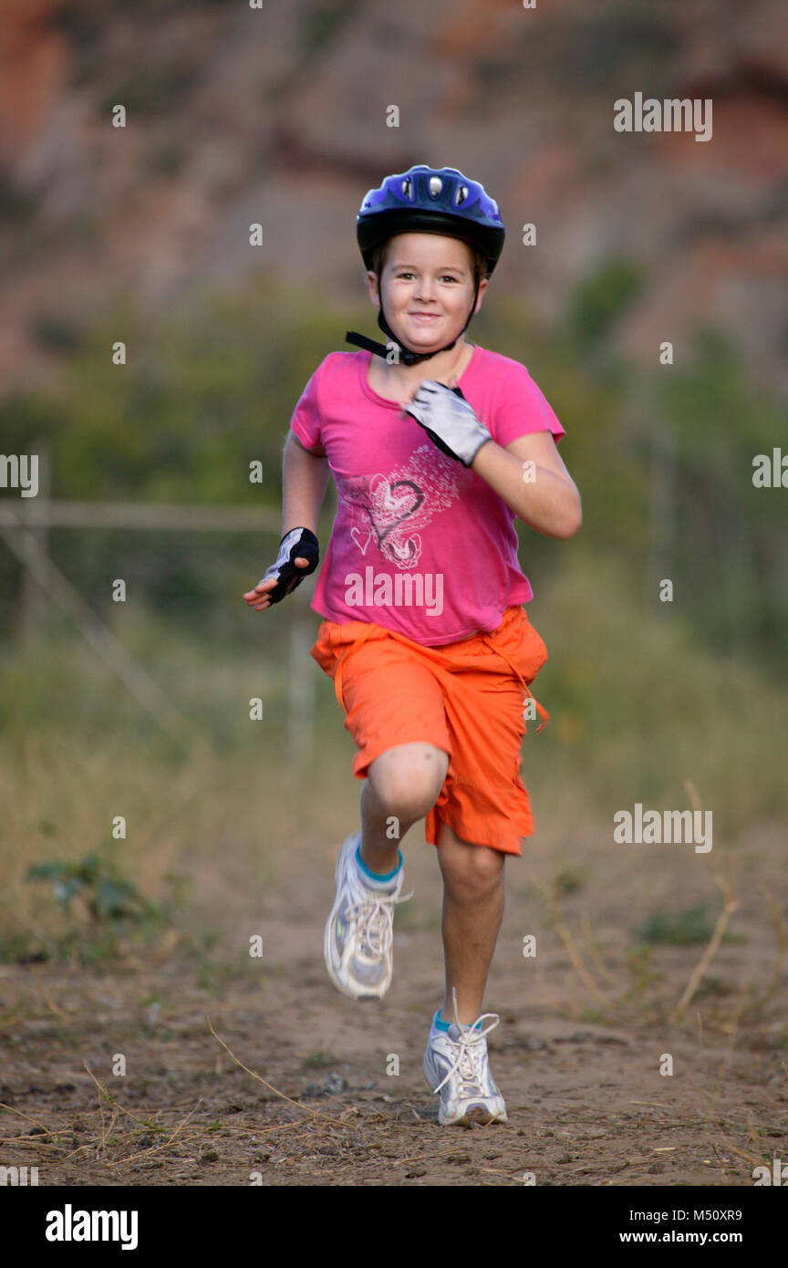 An enthusiastic child wearing a cycling helmet and sprinting towards the camera (model released) Stock Photo