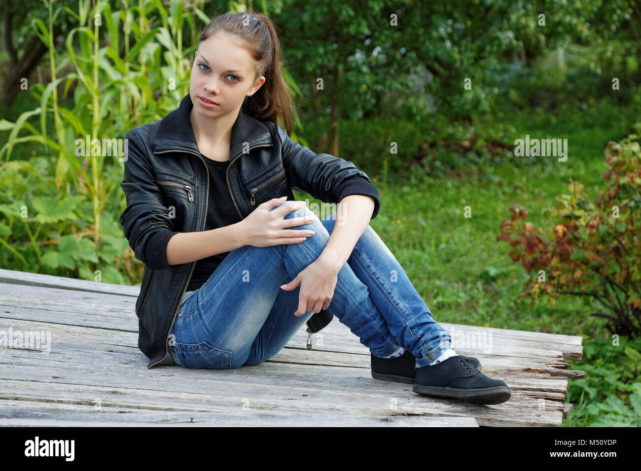 The girl sitting on wooden boards in a summer garden Stock Photo - Alamy
