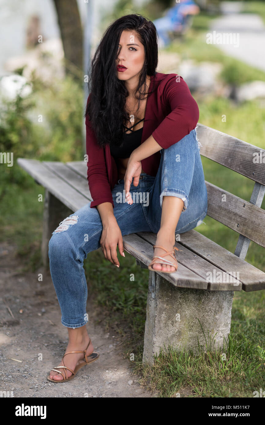 Young woman sitting casually on a wooden bench Stock Photo