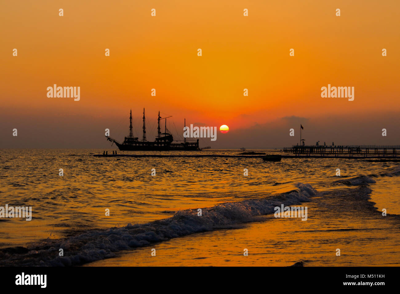 Pirate ship in the ocean, beautiful sunset over the ocean, in the sea, waves at the beach, red colored Stock Photo