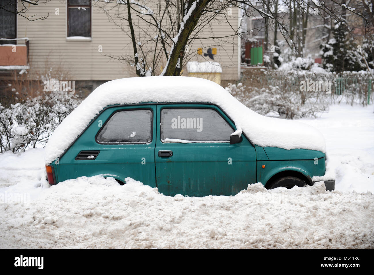 Green Polski Fiat 126 covered in snow, parked on the pavement in Wolomin in Mazowiecki region of Poland Stock Photo