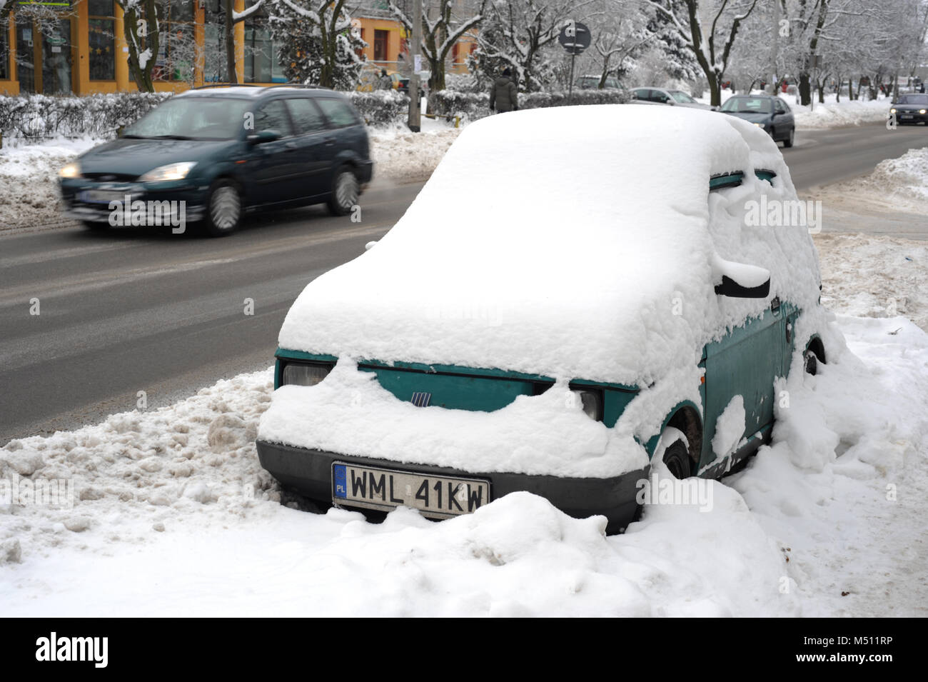 Green Polski Fiat 126 covered in snow, parked on the pavement in Wolomin in Mazowiecki region of Poland Stock Photo