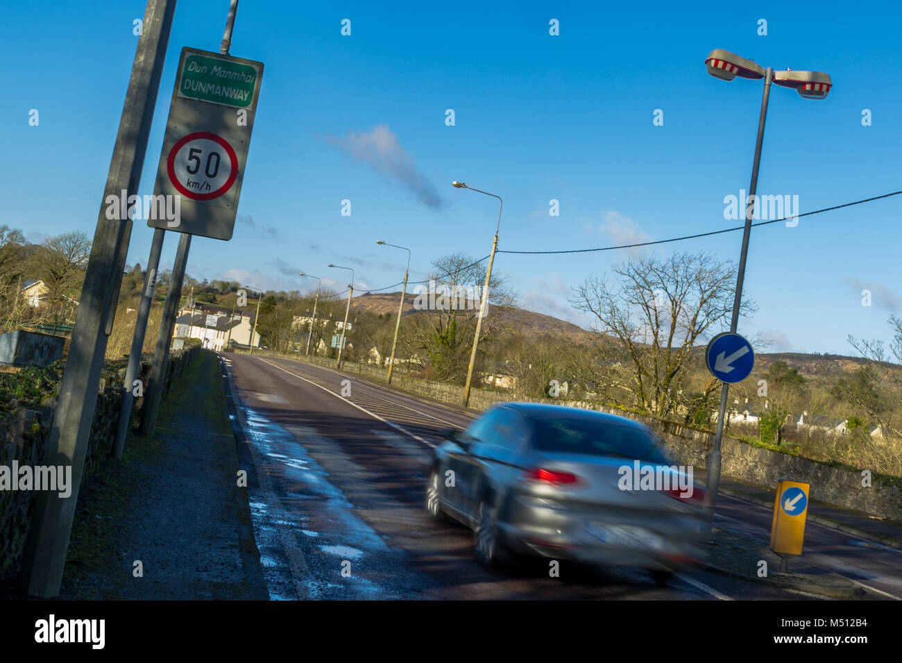 Speeding car passes a 50 km/h speed limit sign in Dunmanway, County Cork, Ireland. Breaking the speed limit, road safety concept. Stock Photo