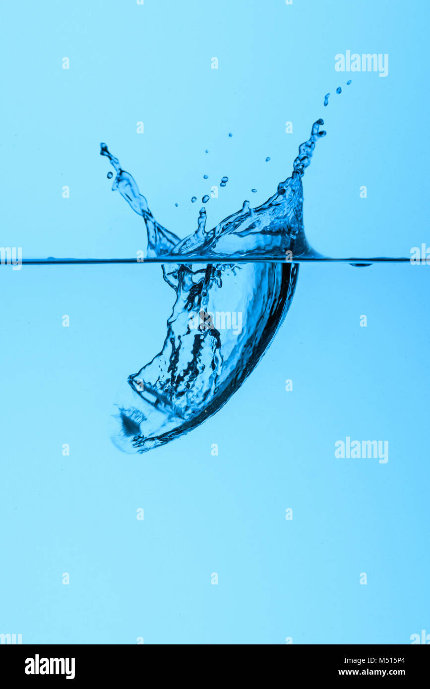 ice cube in water with splash, isolated on blue Stock Photo - Alamy