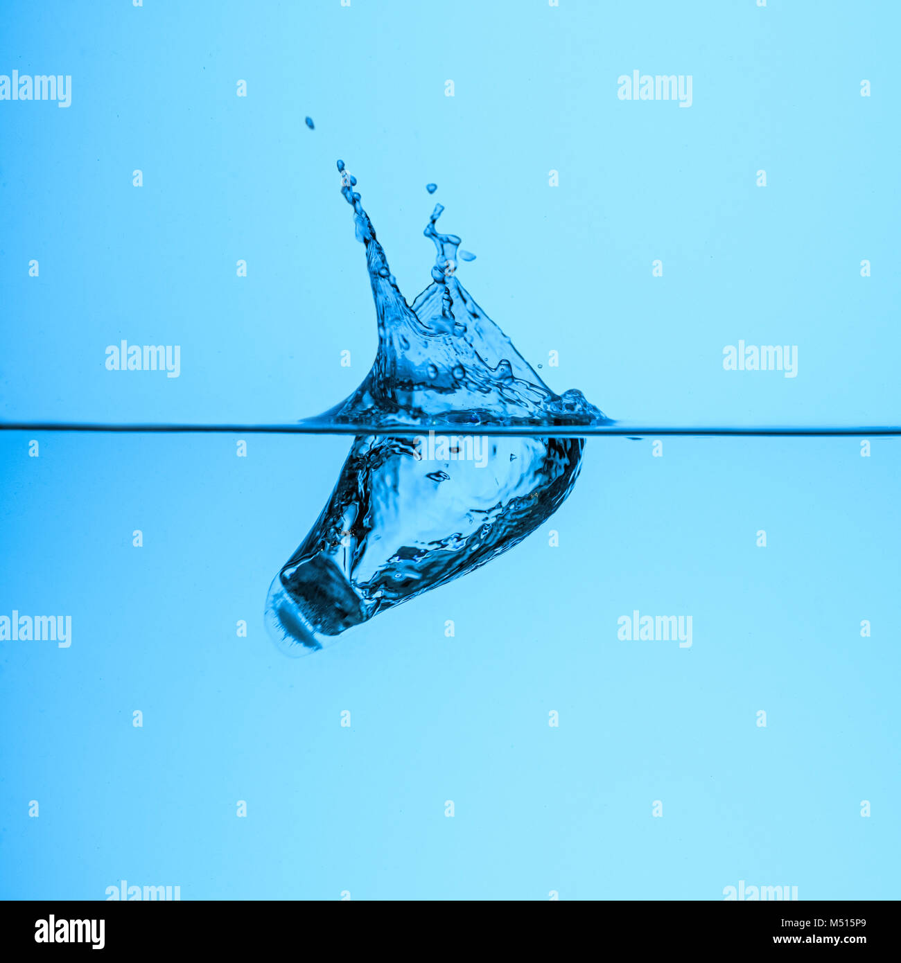 ice cube in clear water, isolated on blue Stock Photo - Alamy