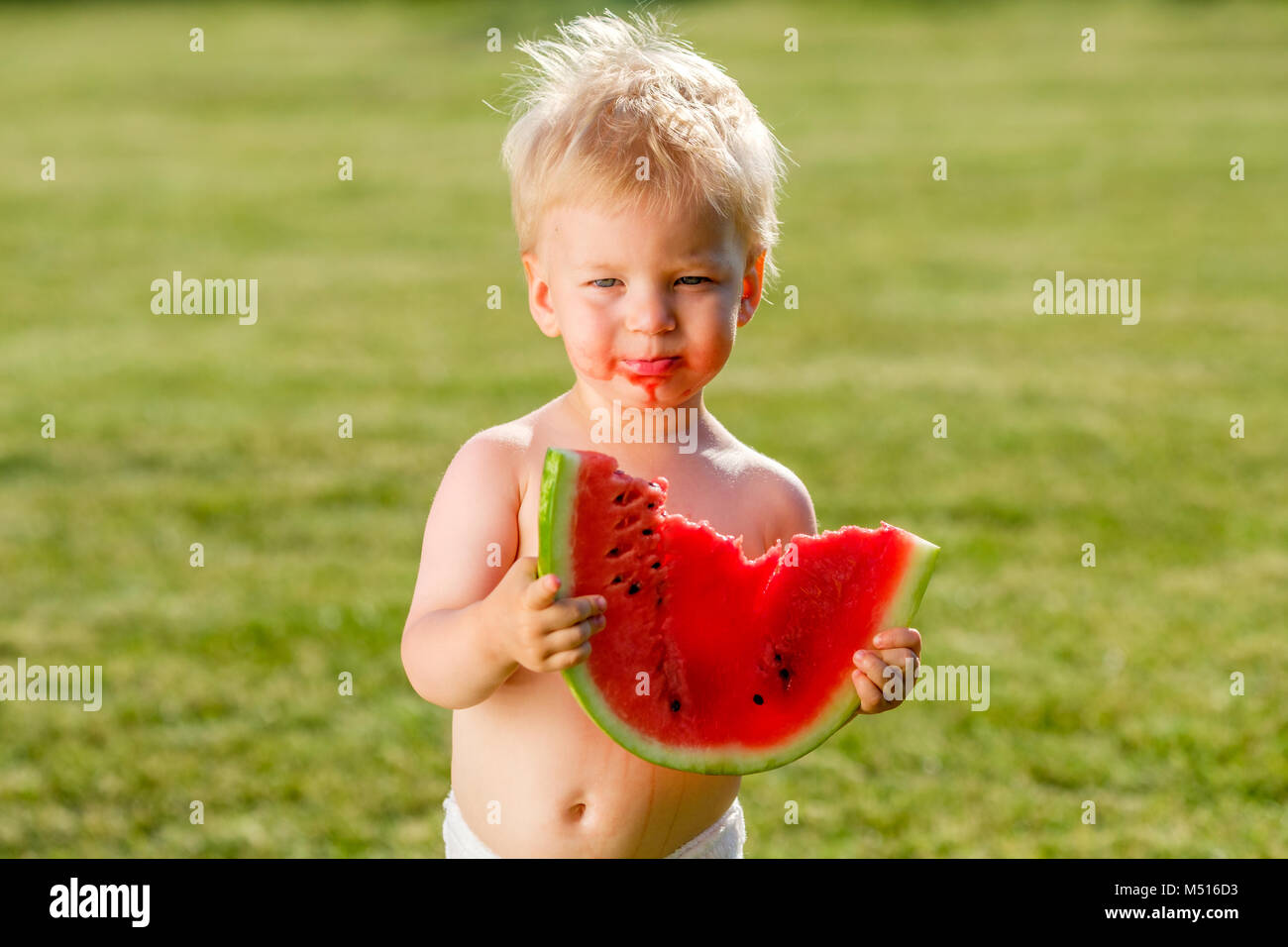 One year old baby boy eating watermelon in the garden Stock Photo