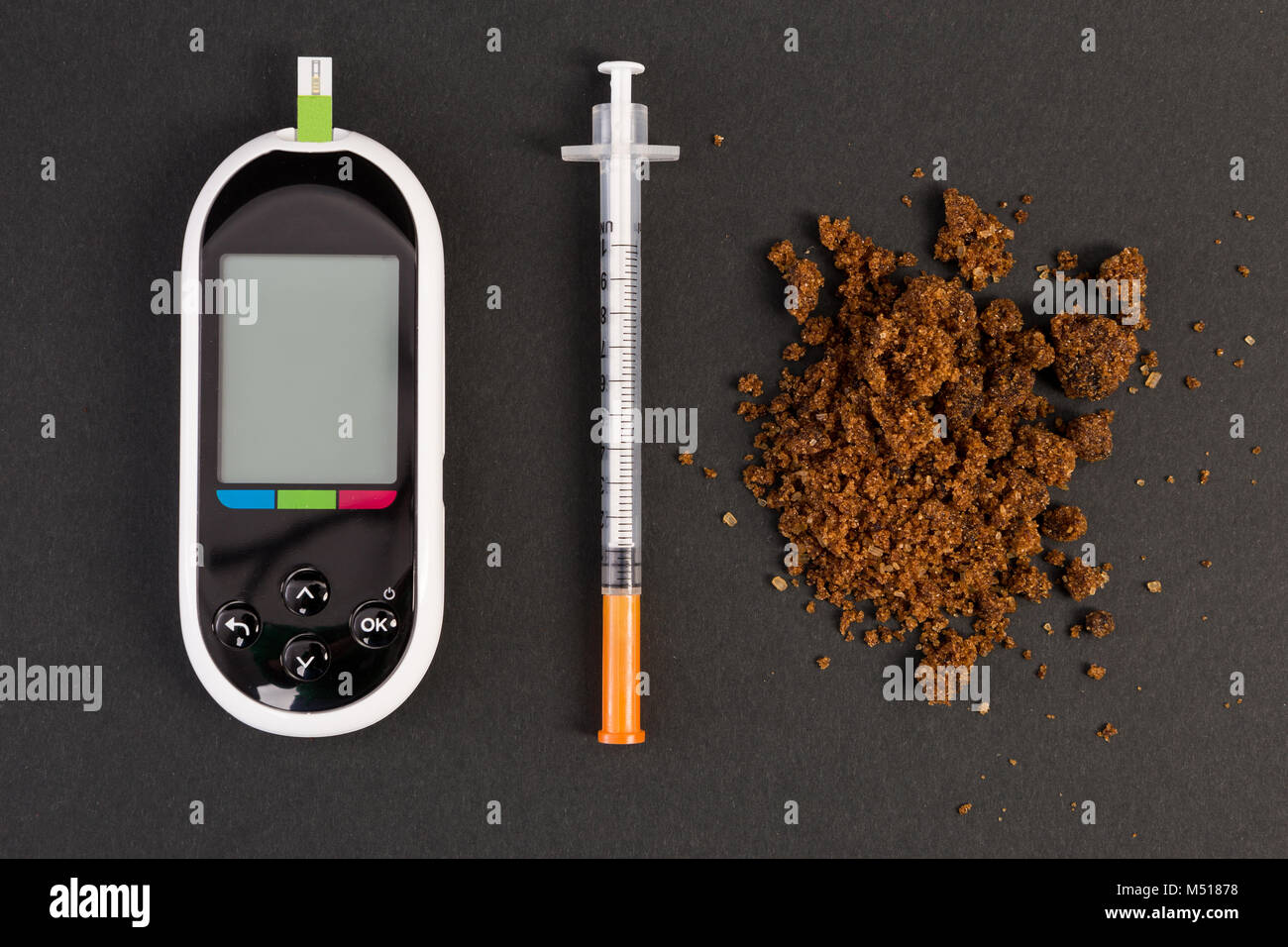 Hypoglycemia concept with glaucometer insulin syringe and healthy natural brown sugar pile Stock Photo