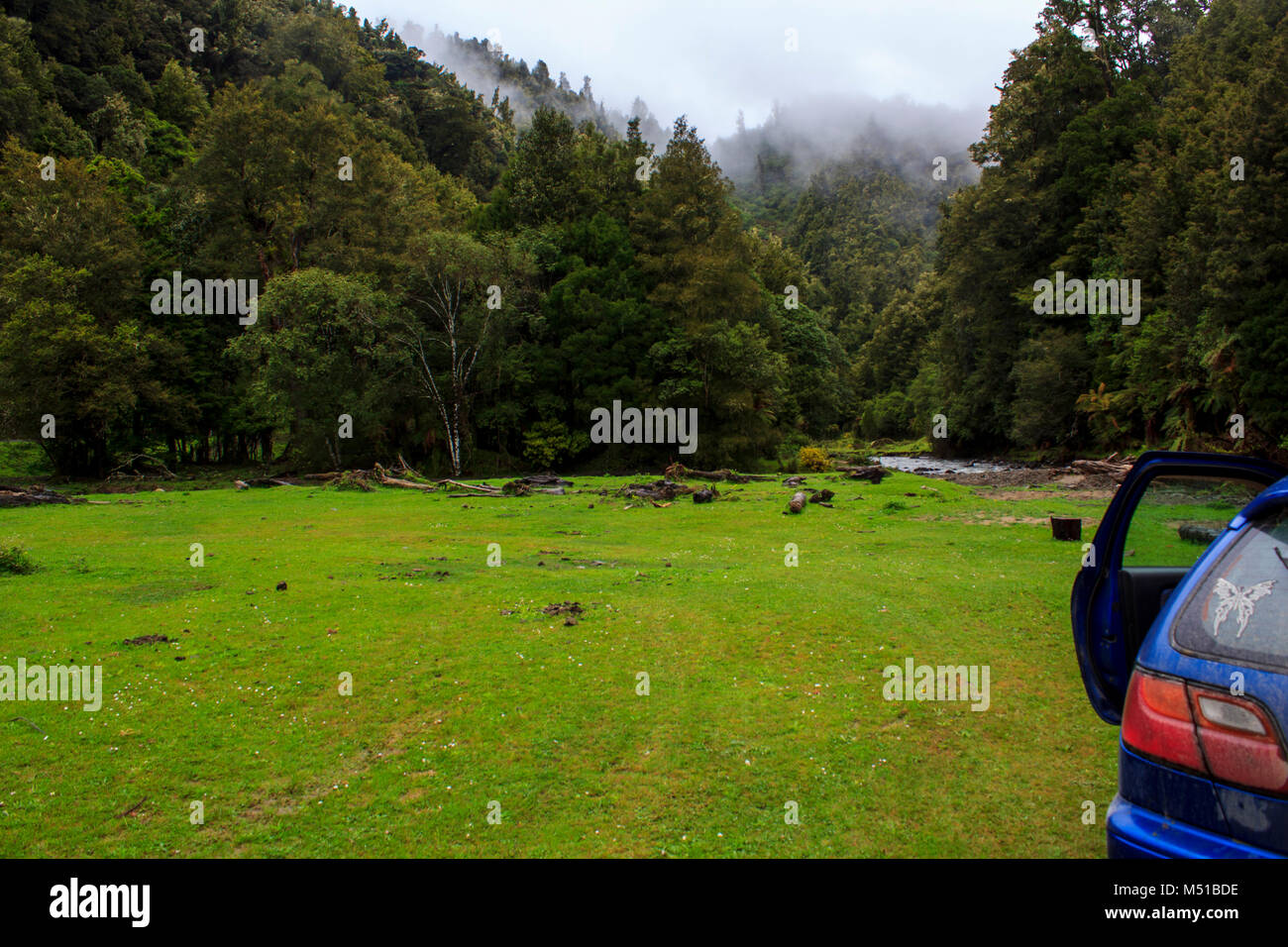 Car parked in cinematic landscape, mountain forest and river Stock Photo