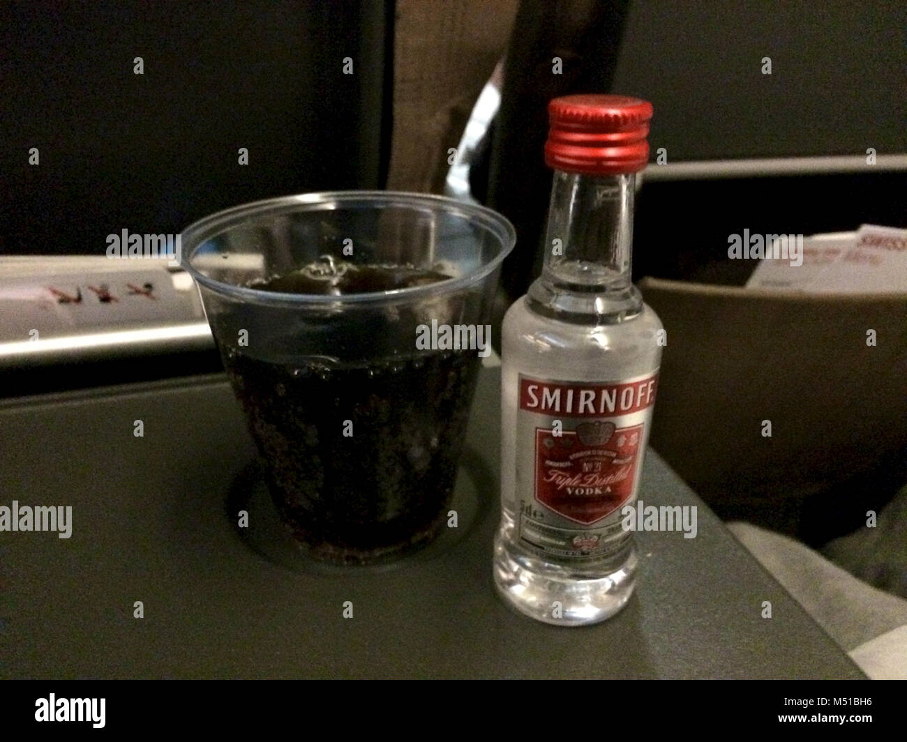 ZURICH, SWITZERLAND - MAR 31st, 2015: SWISS serves alcohol in economy class on a long haul flight, enjoy vodka coke Stock Photo
