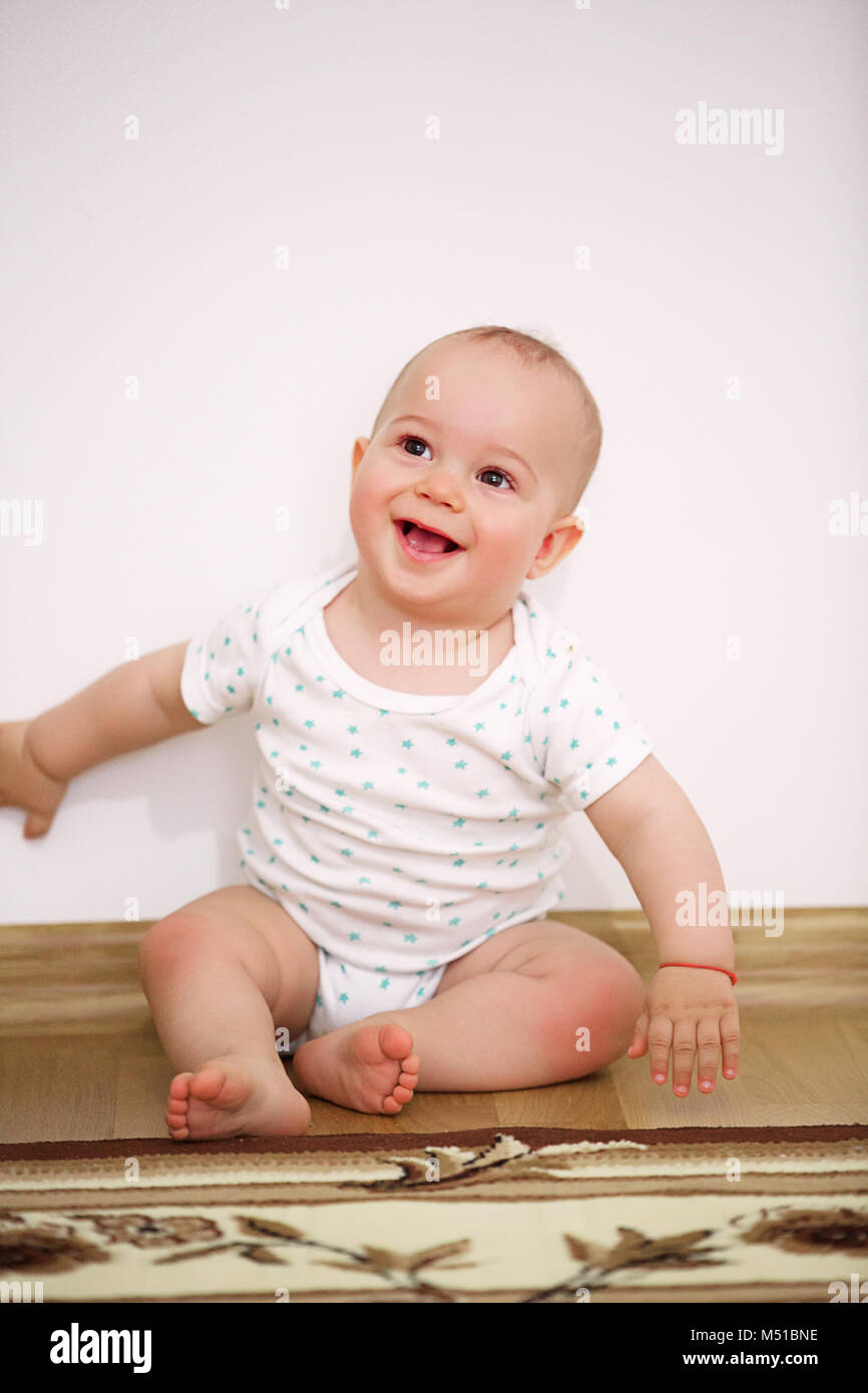 Happy baby boy (1 year old) sitting on floor at children's room Stock