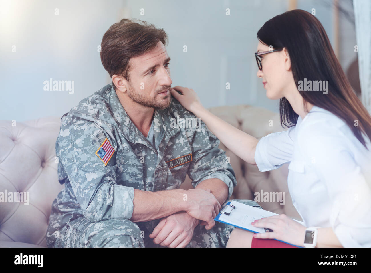 Cheerful female psychologist calming worried soldier Stock Photo