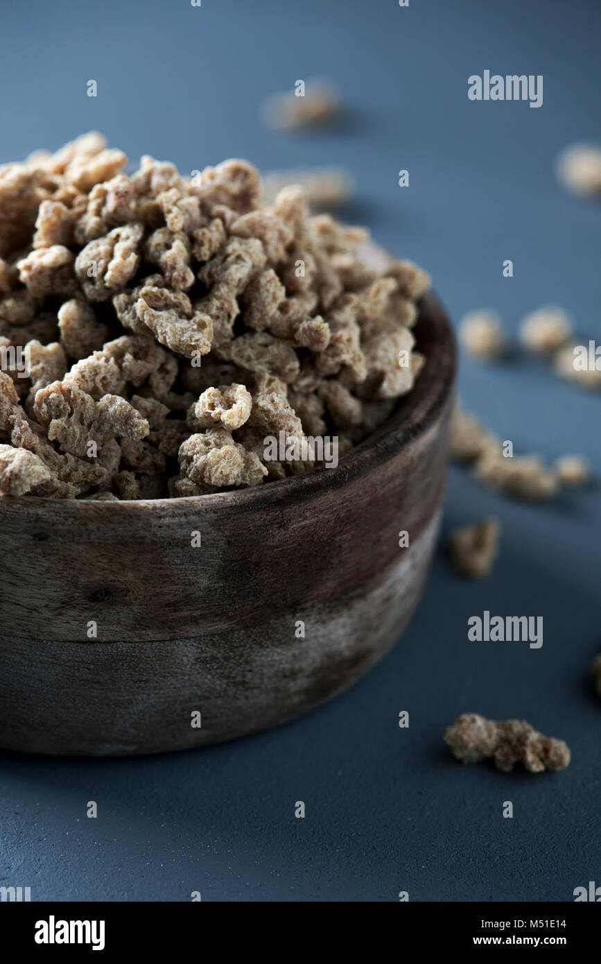 closeup of some chunks of textured soy protein in a rustic wooden bowl, on a gray wooden table Stock Photo